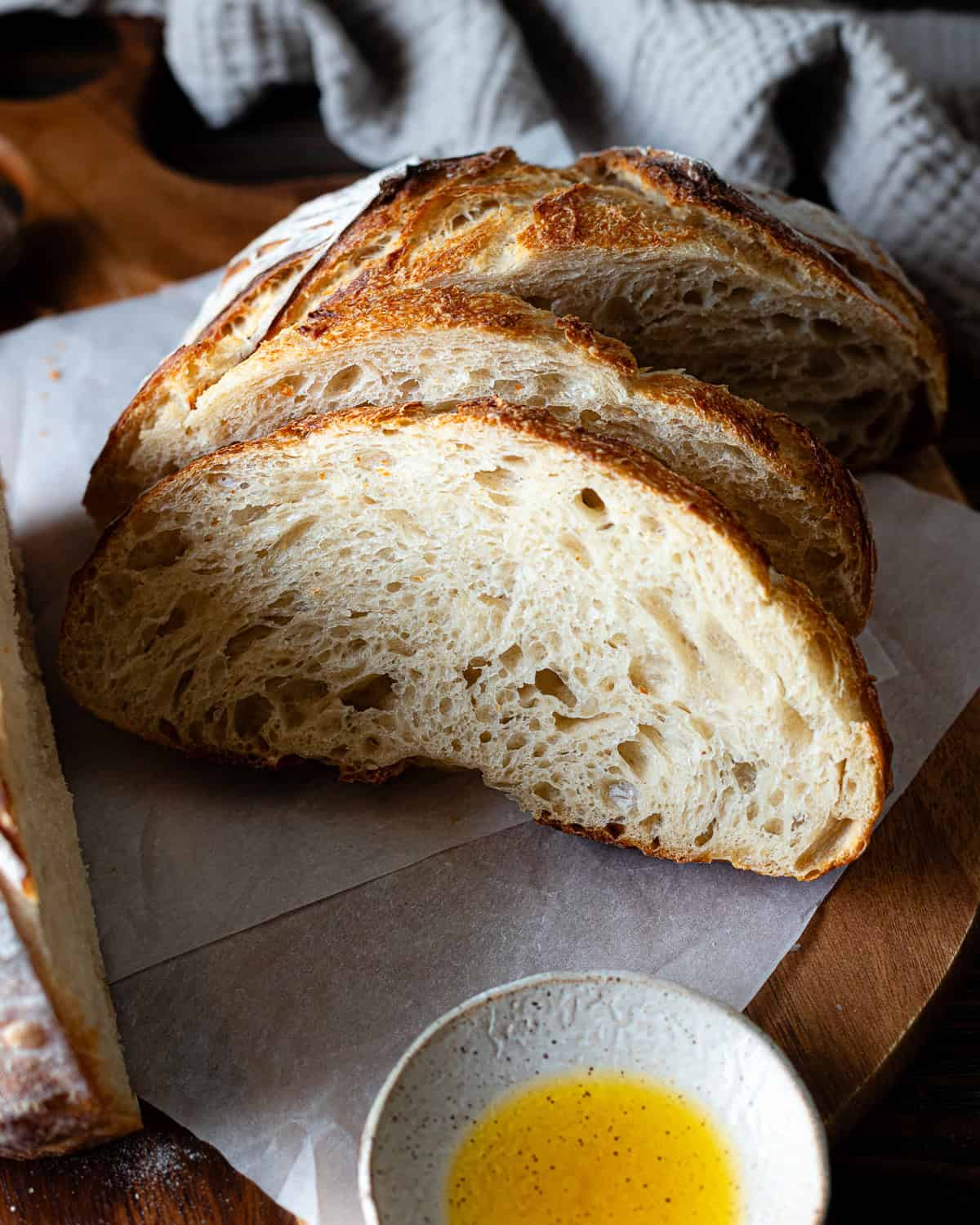 Sliced loaf of bread on a wood cutting board lined with parchment paper.