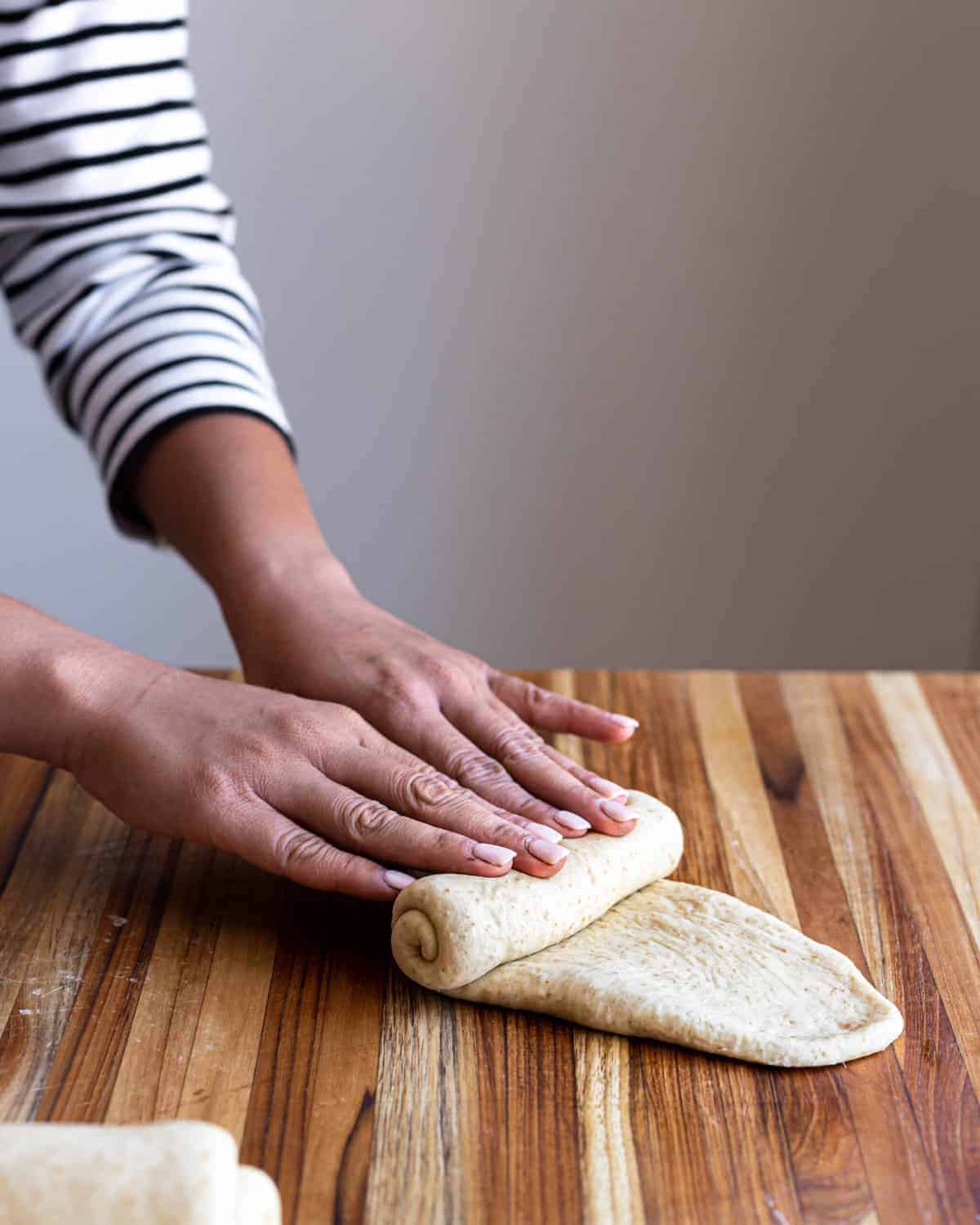 Hands rolling up portion of dough
