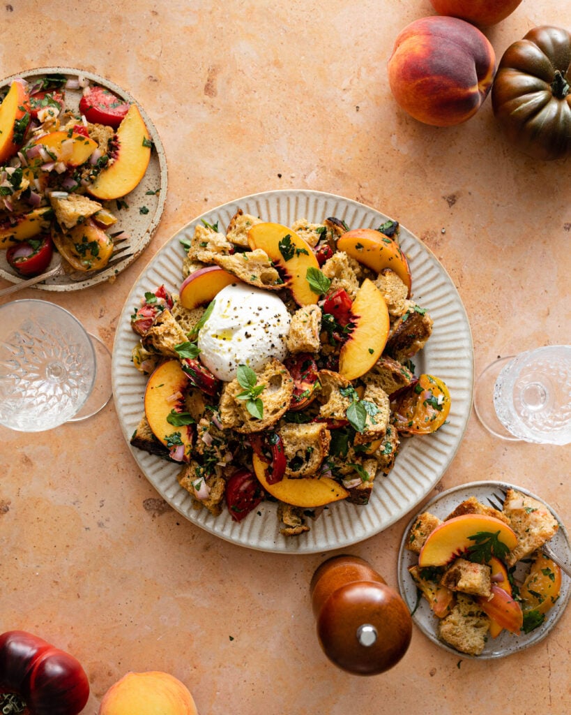 Panzanella on serving plate with two small plates with panzanella salad