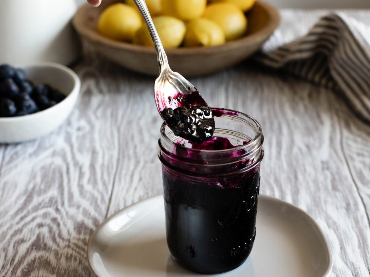 spoon scooping up blueberry preserves in a small jar