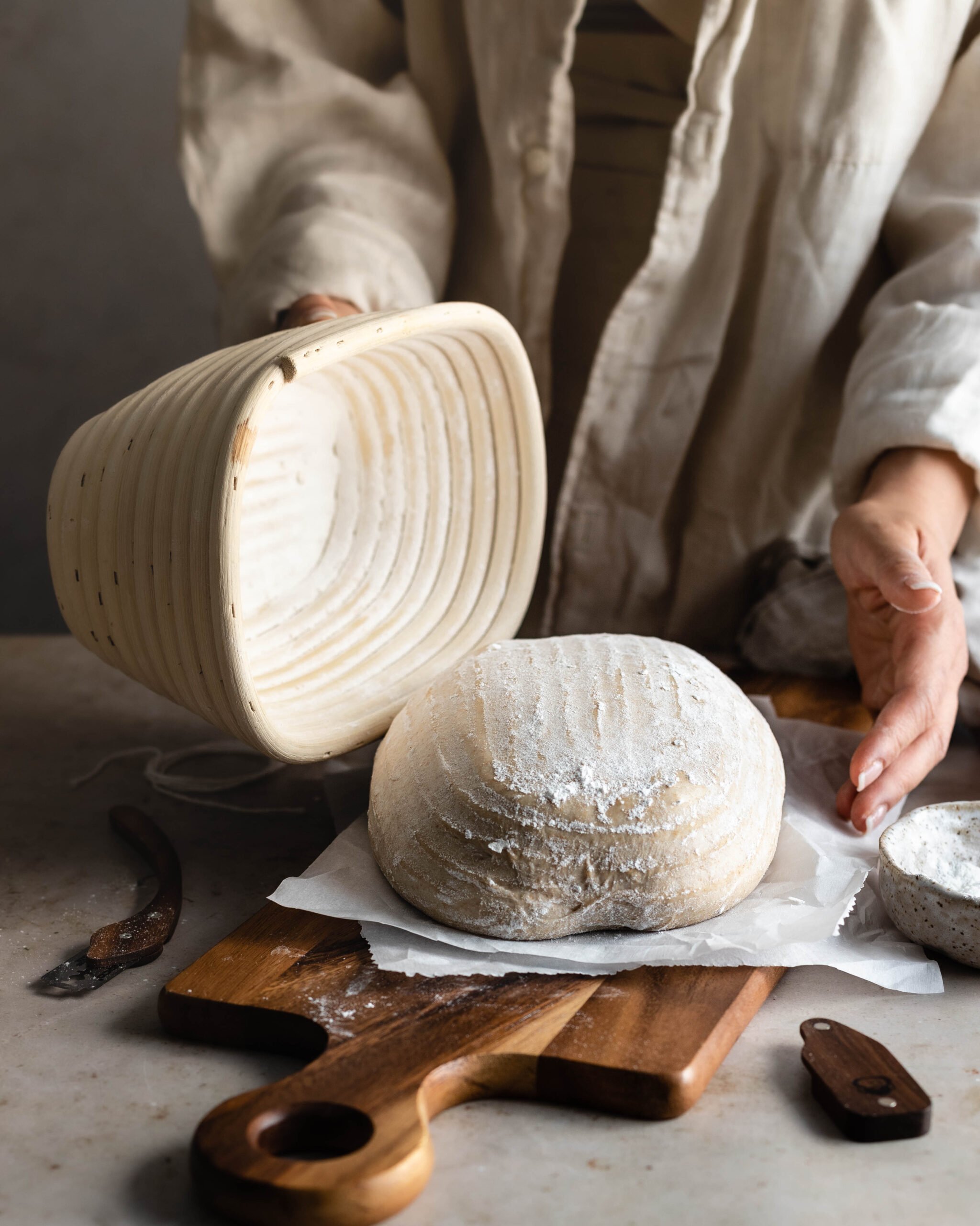 Dough on cutting board with hand holding a bread basket