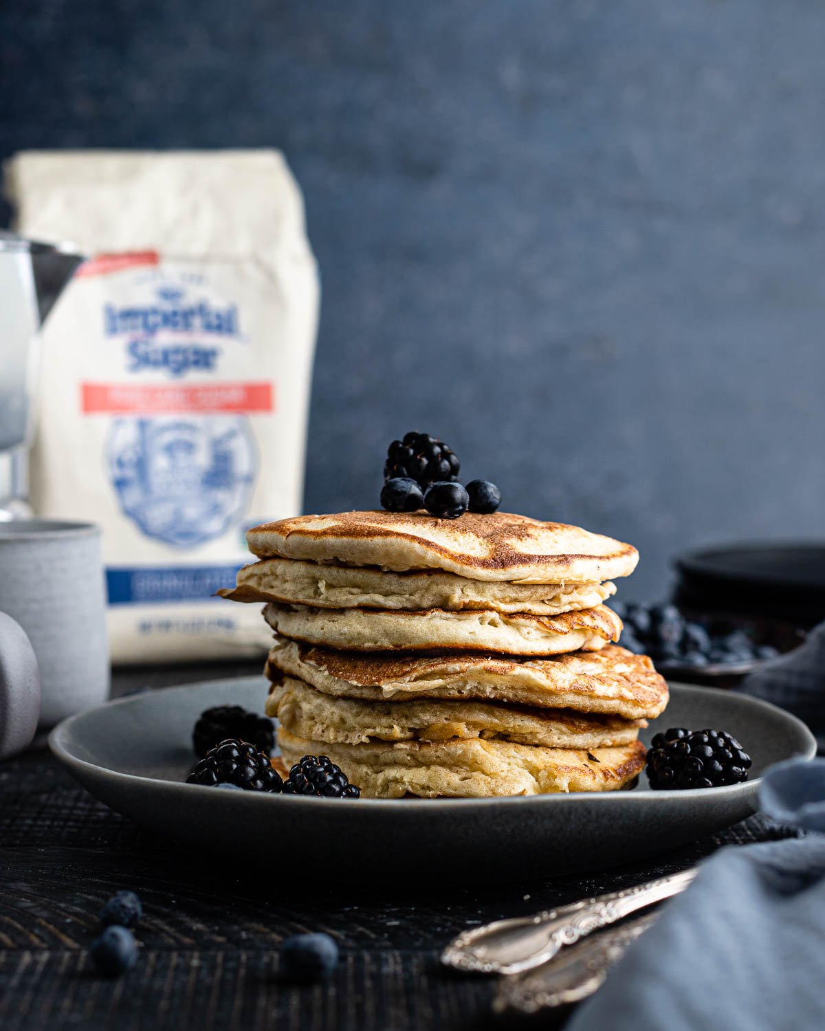 Stack of pancakes arranged on a plate with berries. 