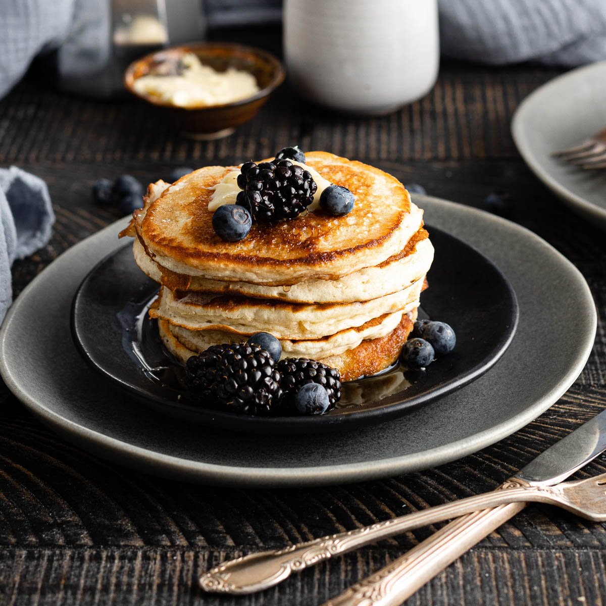 Stack of pancakes arranged on a plate with berries. 