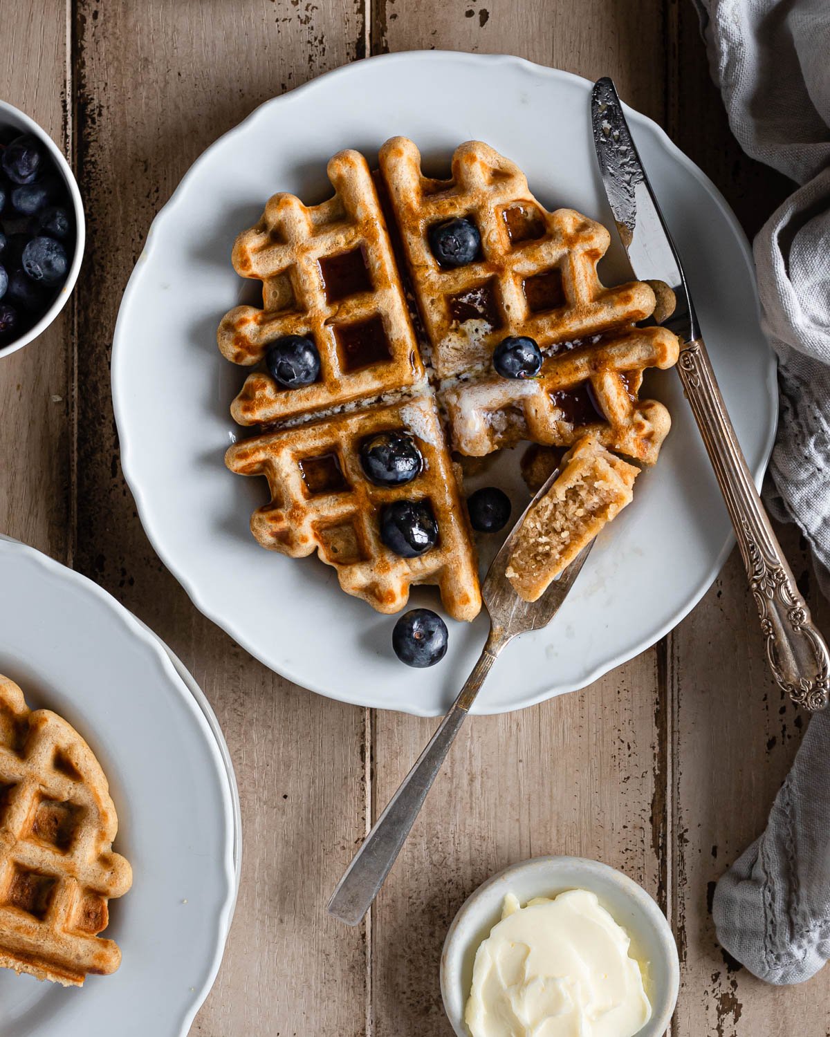 cut waffle with a piece on a fork with syrup and blueberries