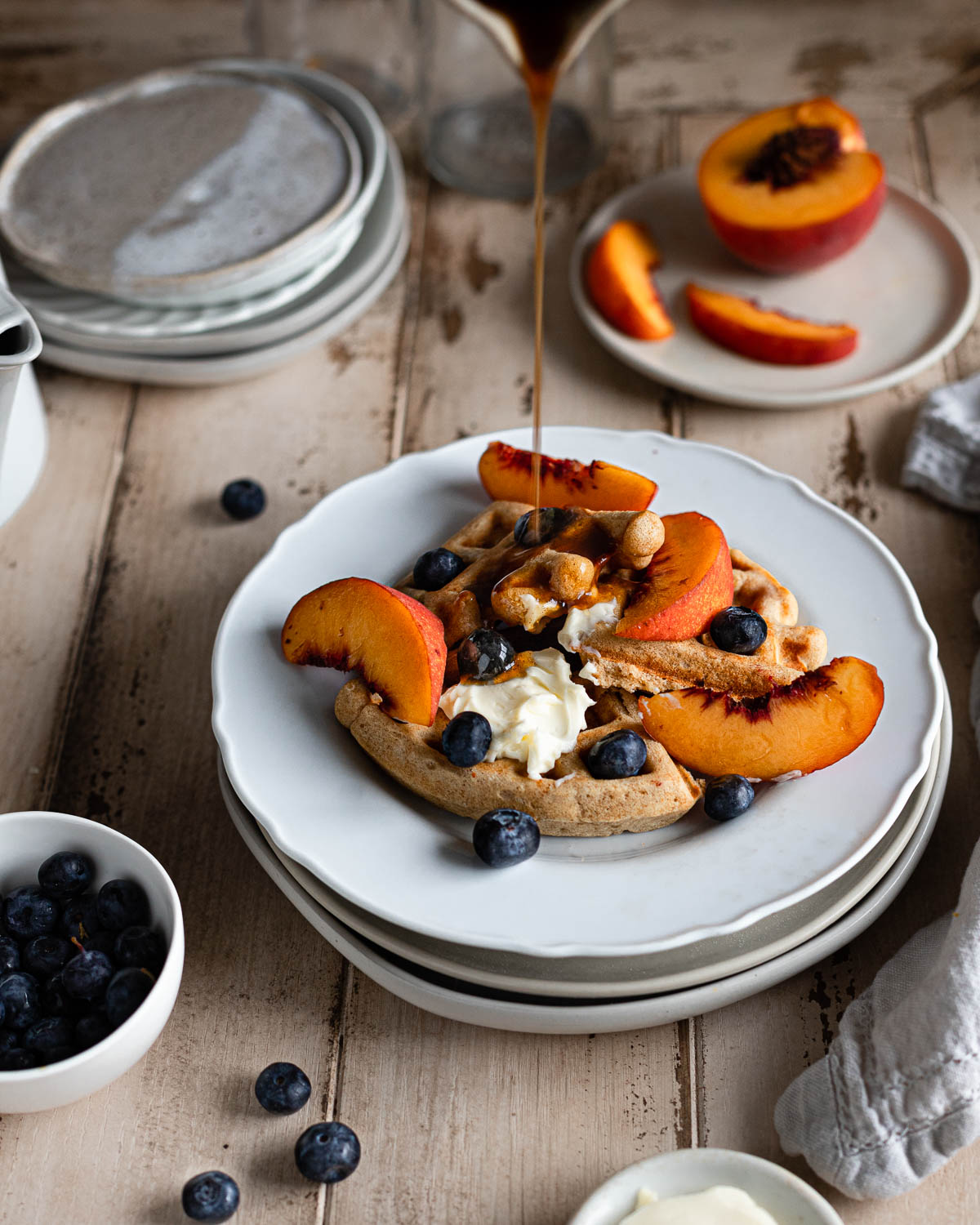 syrup poured on waffle segments with peaches and blueberries