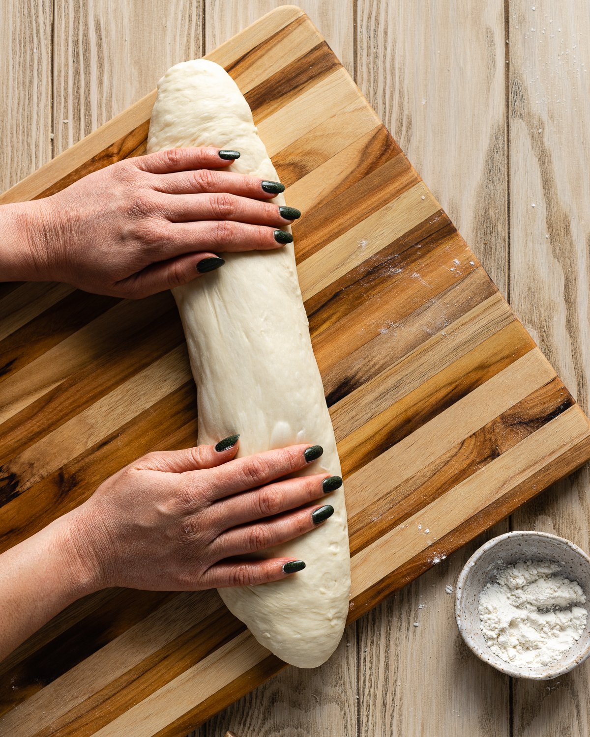 hands shaping dough into a long baton