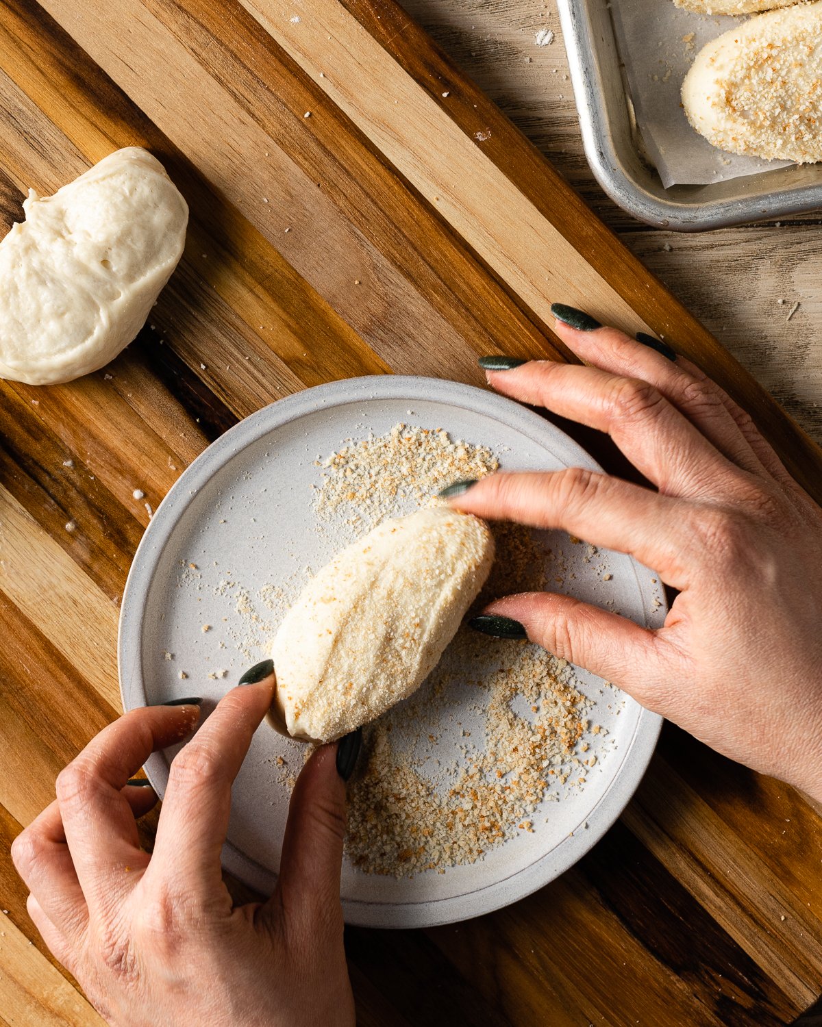 Rolling dough in bread crumbs on a plate