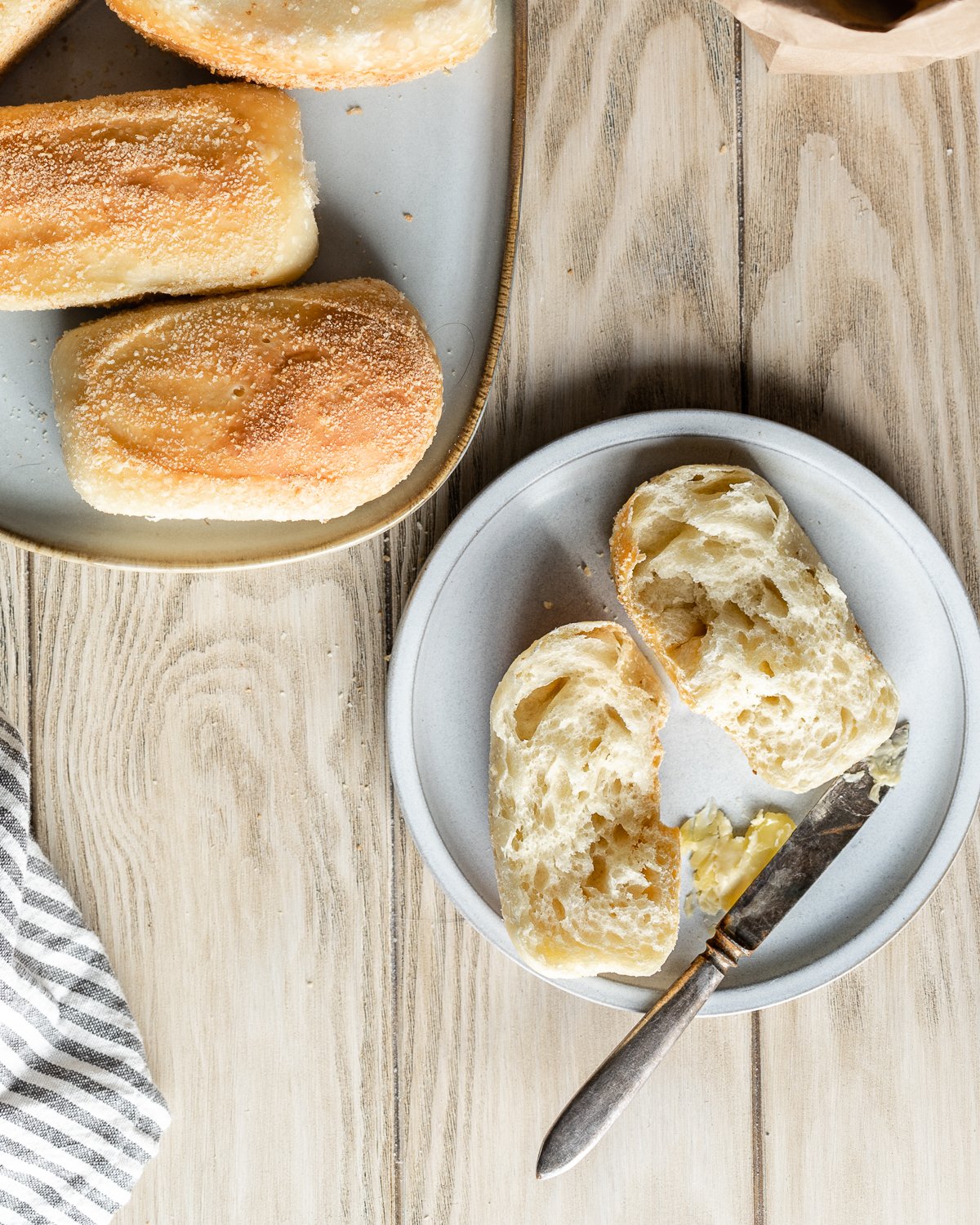 pandesal split in half on a small plate with butter