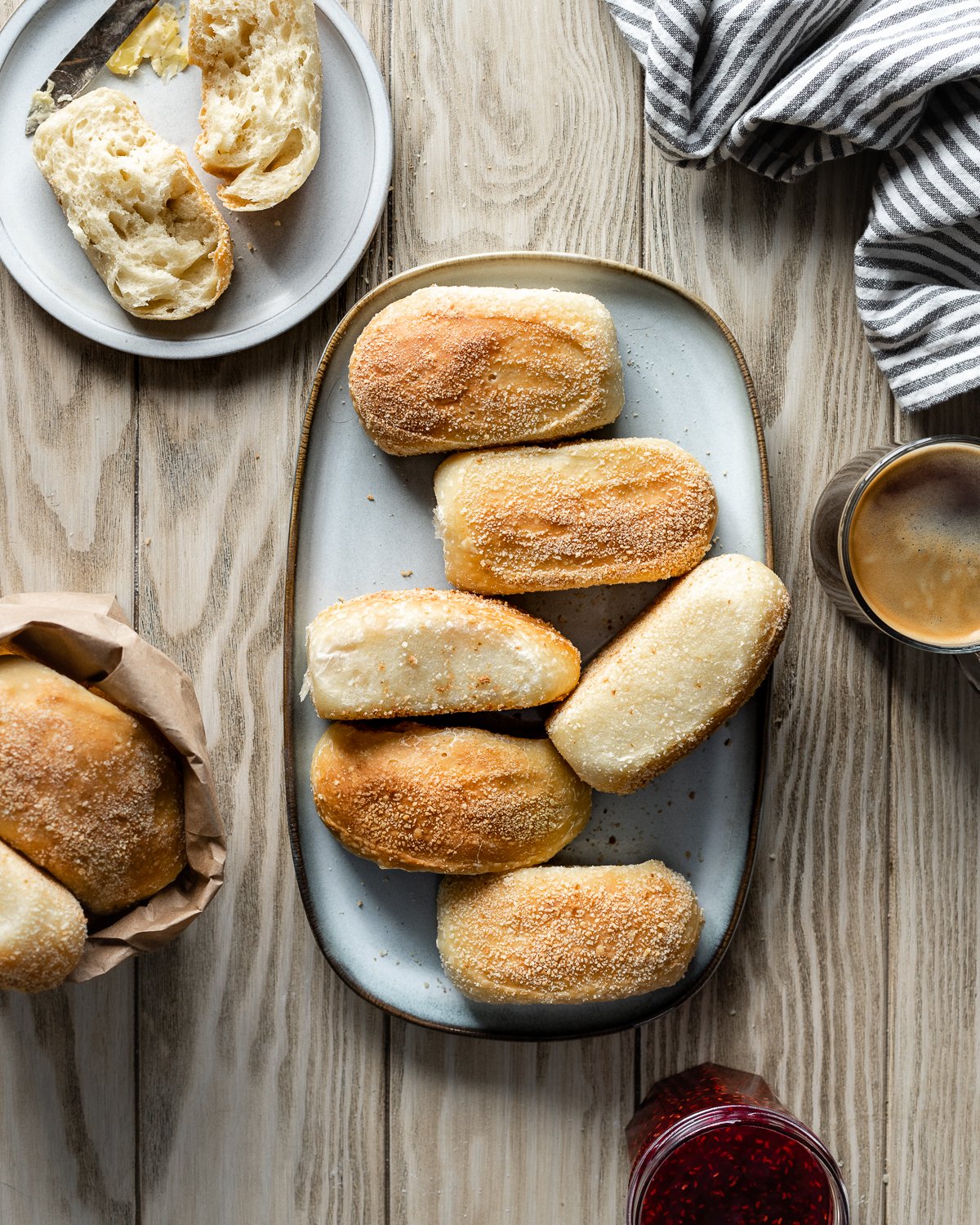 baked pandesal on a platter with jam, coffee and butter