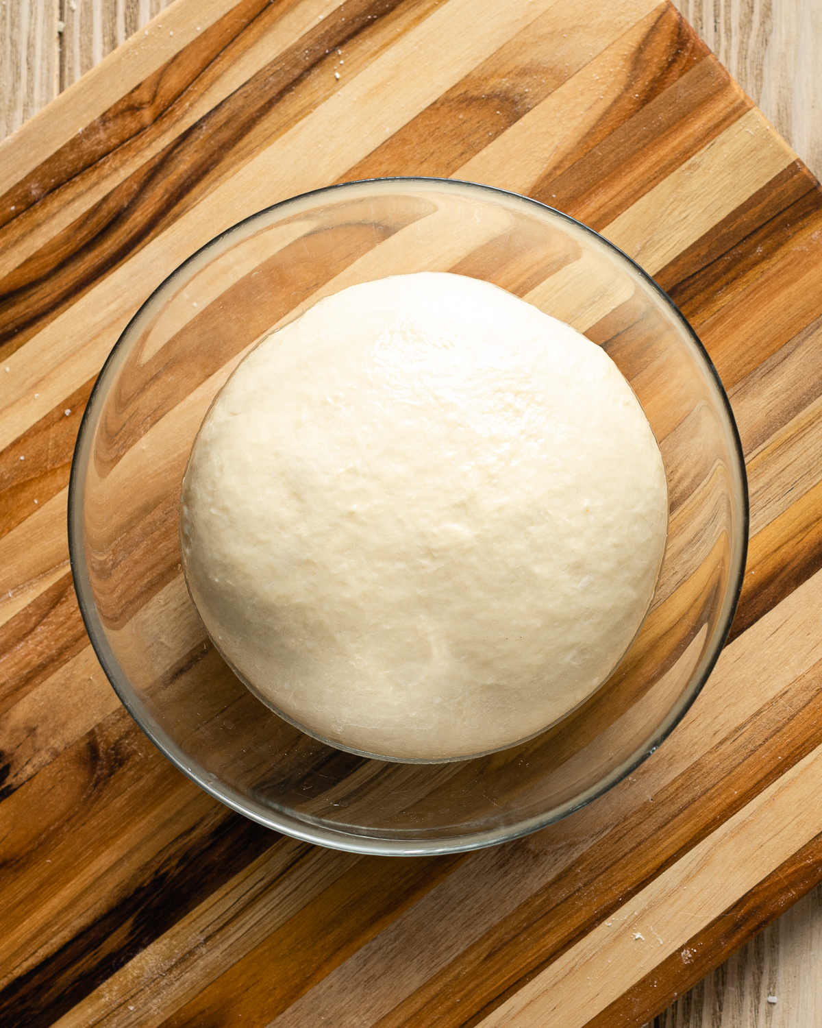 dough in a mixing bowl on top of a cutting board