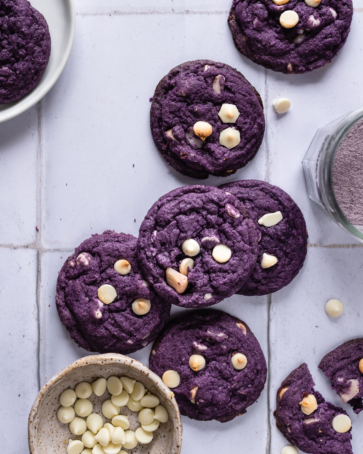stack of purple cookies on tile backdrop with bowl of white chocolate chips