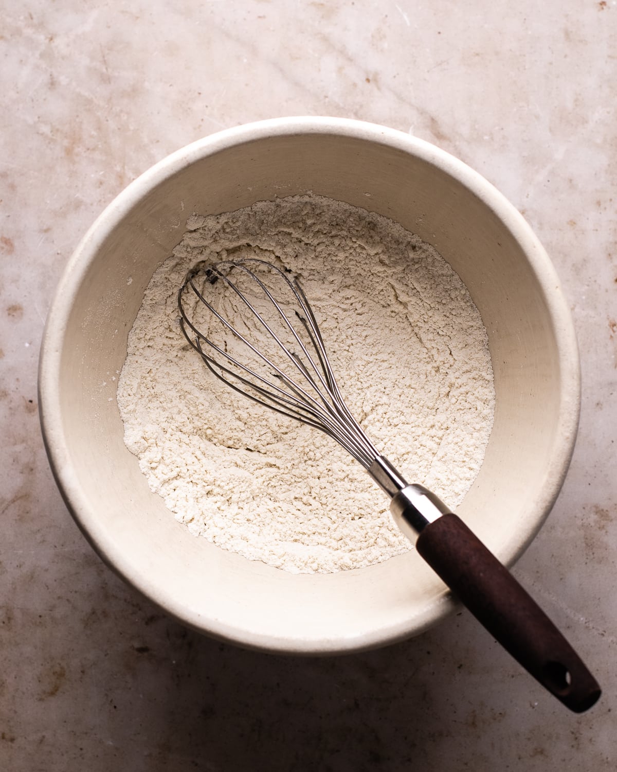 flour in a white mixing bowl with a whisk