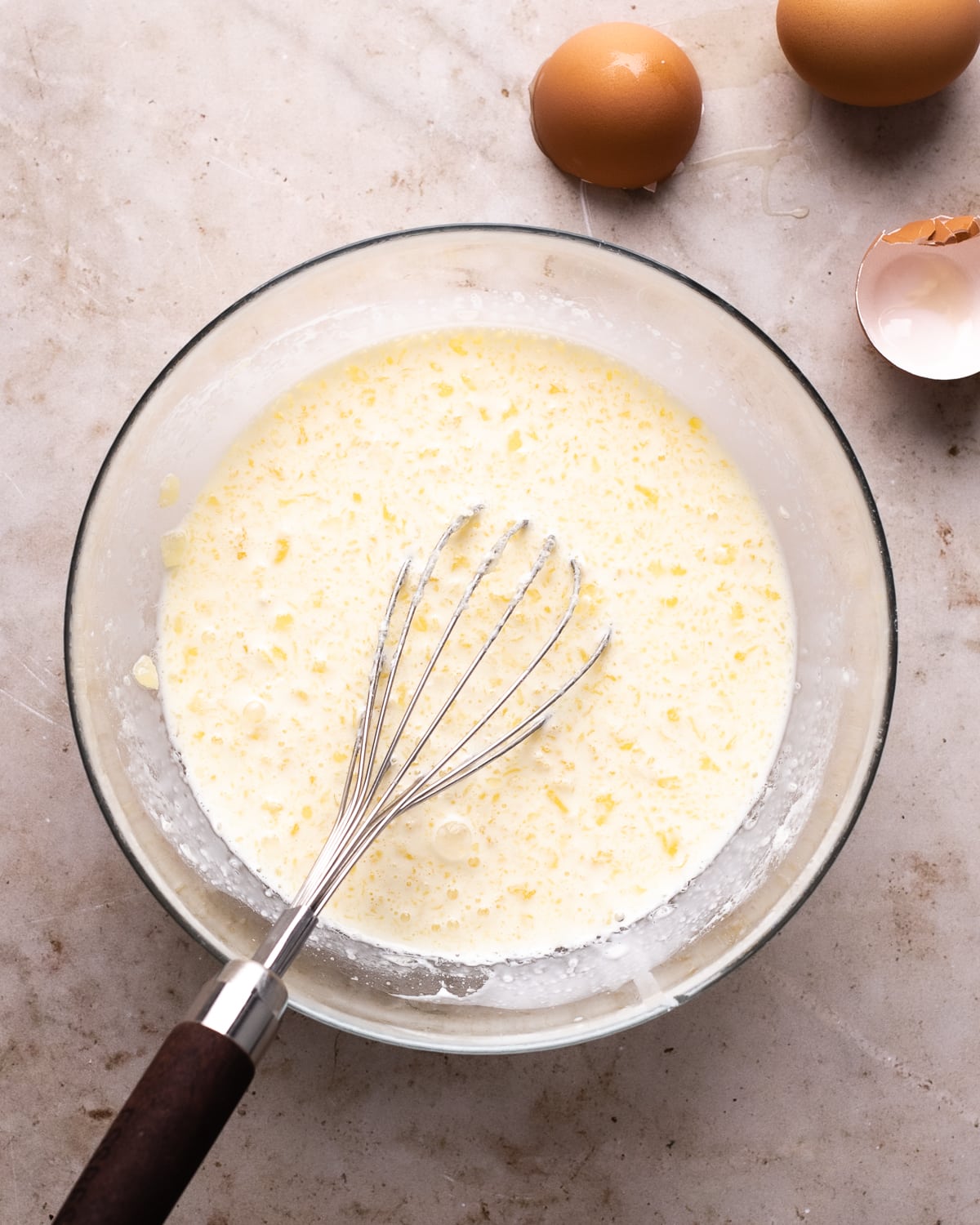 milk whisked with butter pieces inside a glass mixing bowl