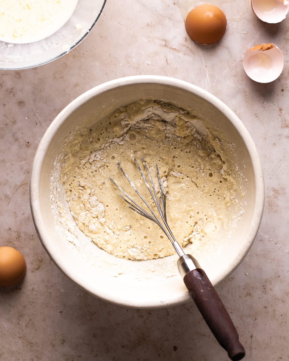thick, bubbly batter with a whisk in a white mixing bowl. 