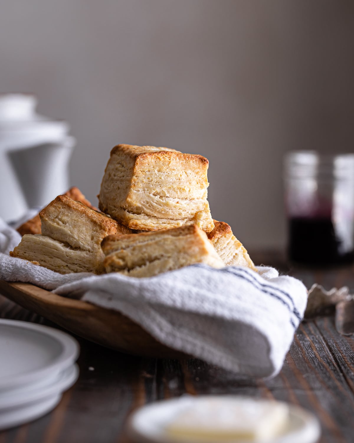 Stack of biscuits on a wooden bowl lined with a tea towel