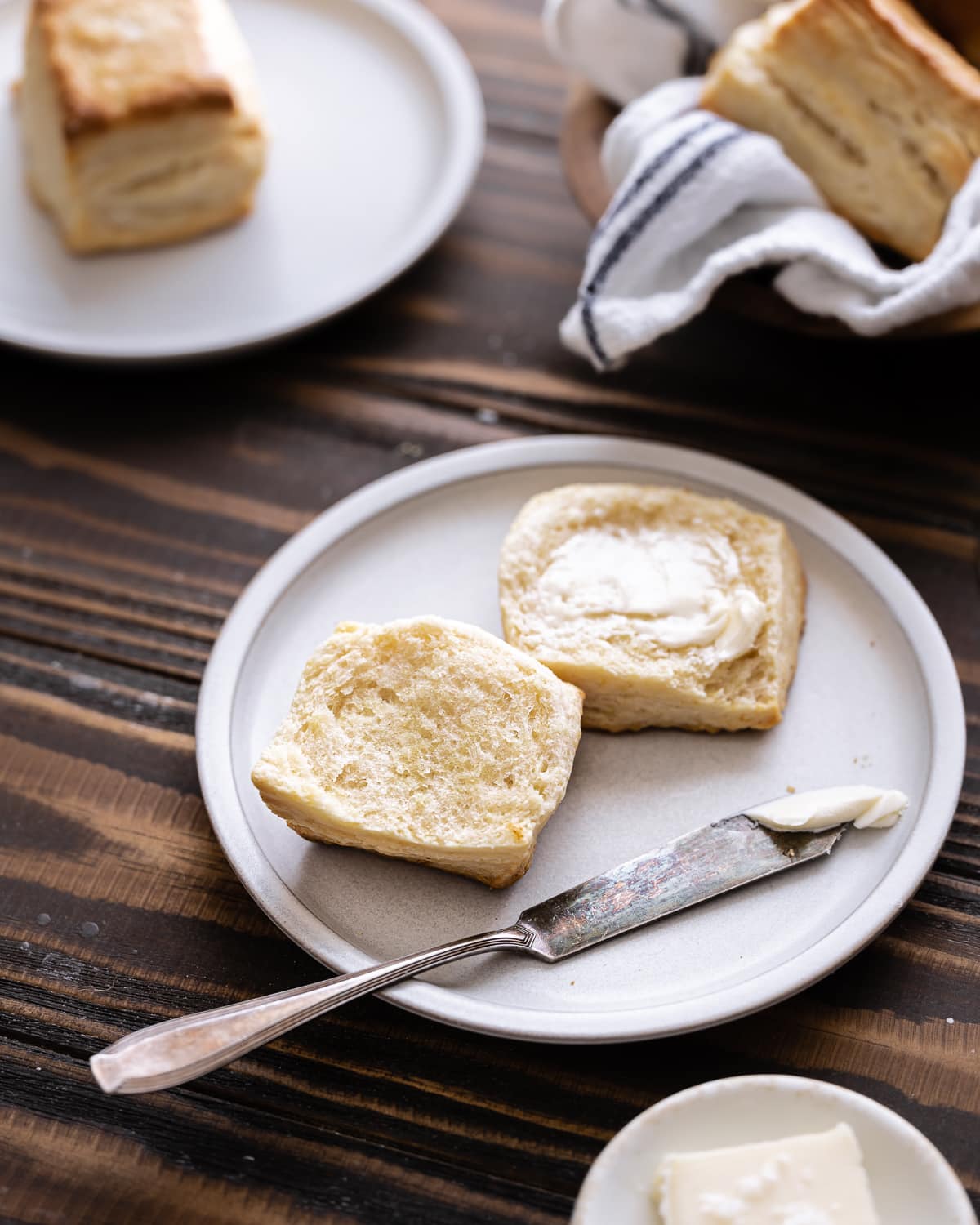 Split biscuit with butter on a small plate.