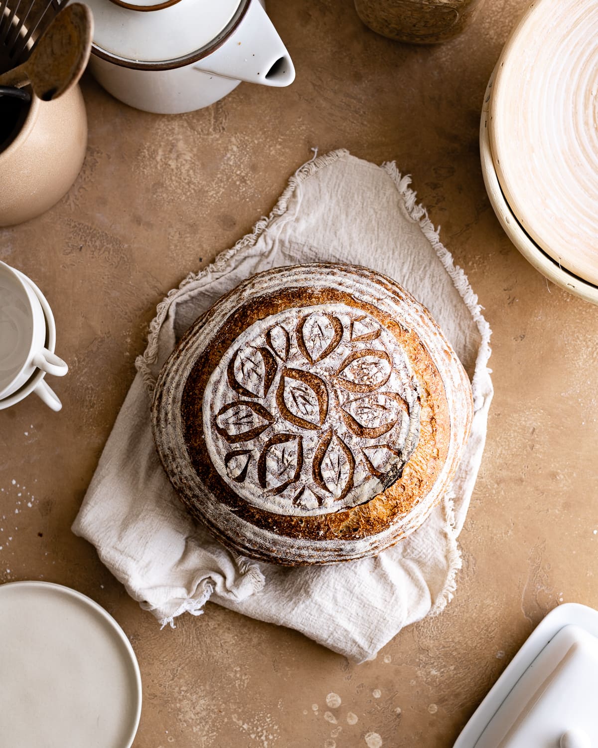 round sourdough bread with leaf scoring design on top on a napkin