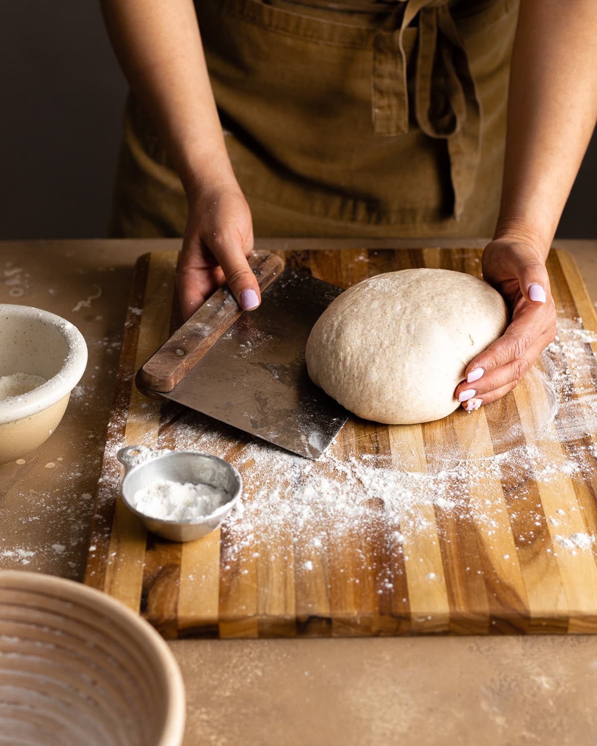 hands rounding dough on a wood cutting board