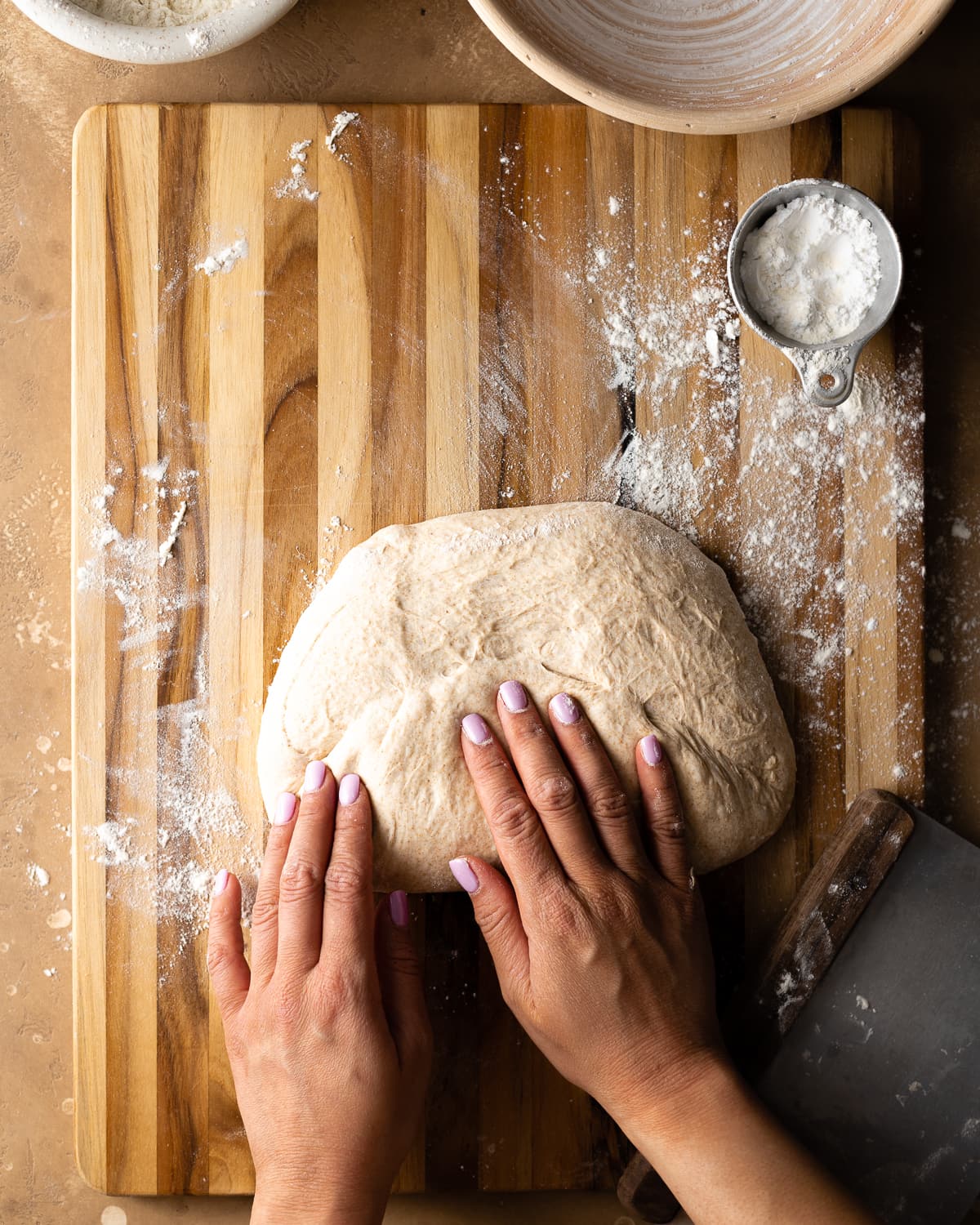 Hands folding bottom portion of dough towards center