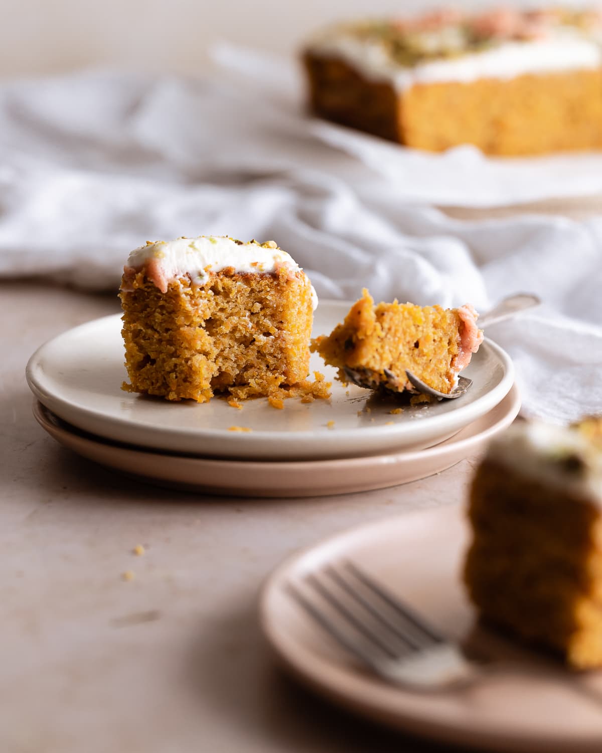 slice of carrot cake on a stack of plates with a bite taken out