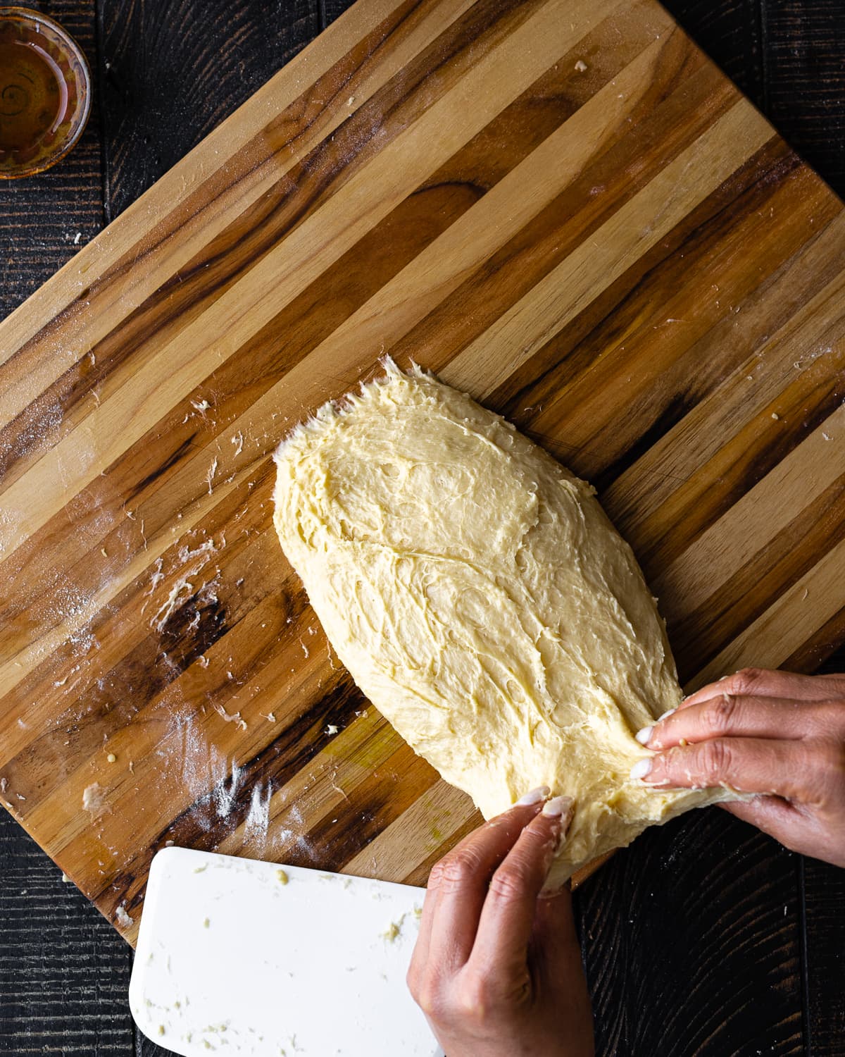 hands holding dough on wooden cutting board 