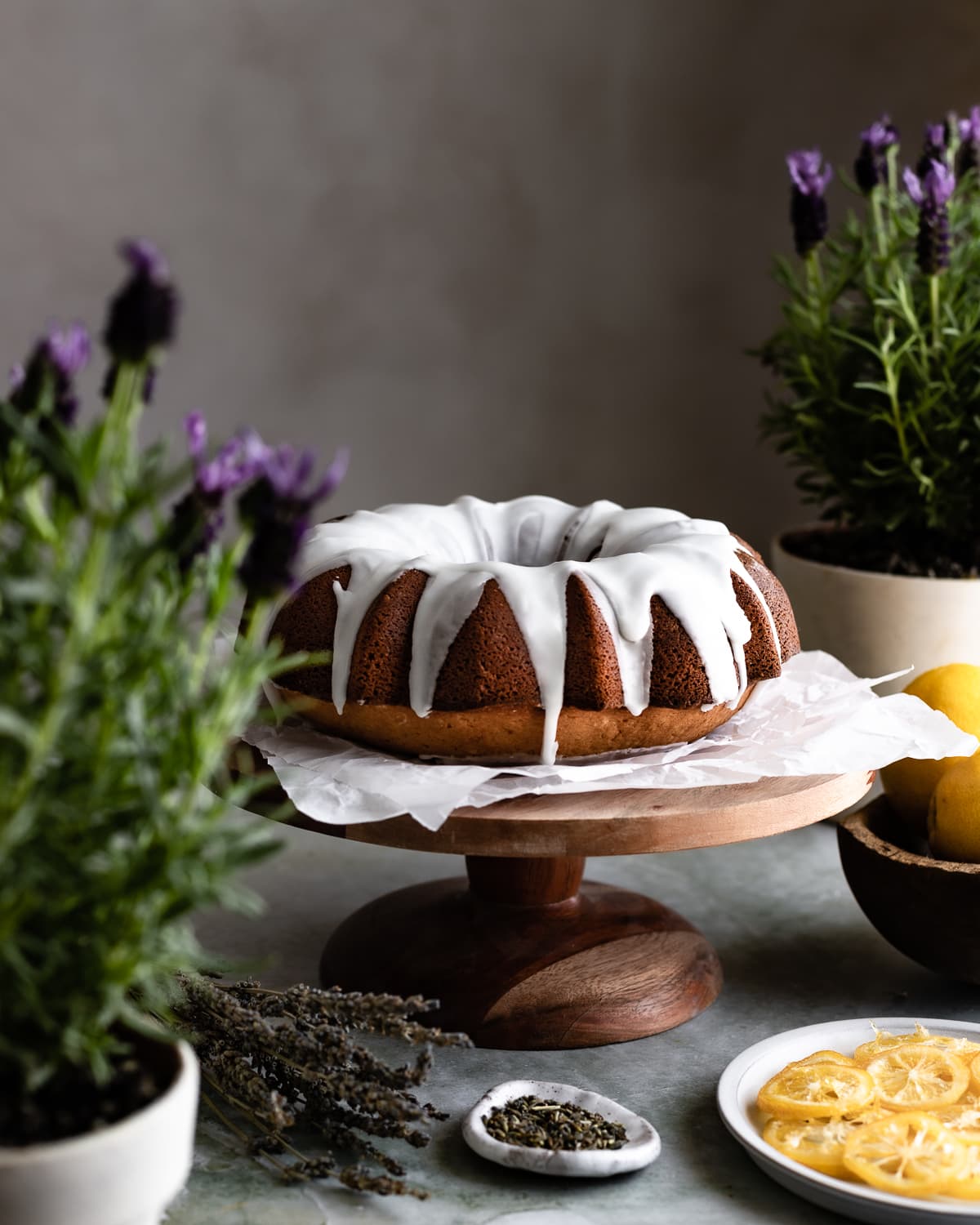 Bundt cake with white icing on a wood cake stand