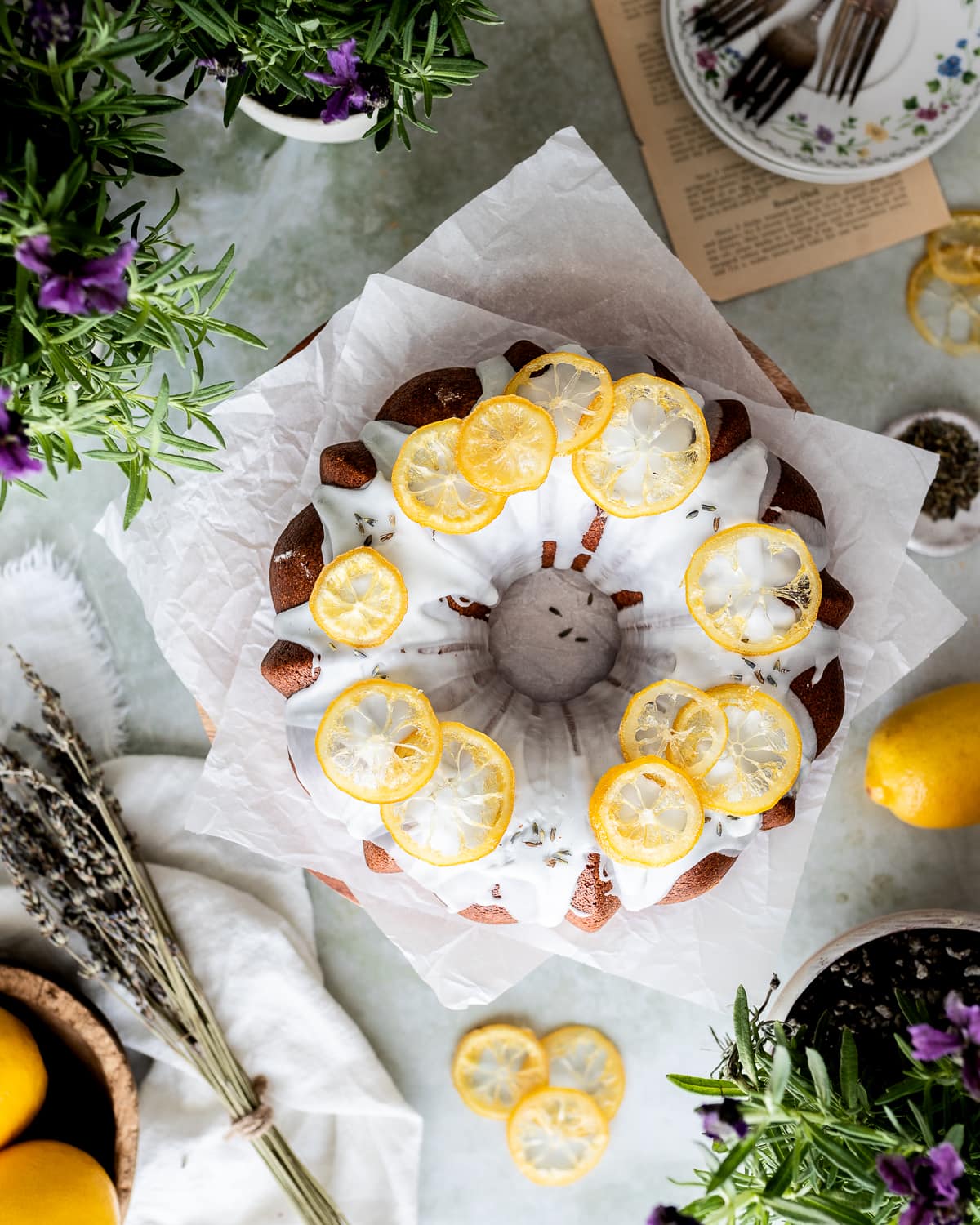 lemon bundt cake with white glaze on two pieces of parchment paper with lemon slices on top