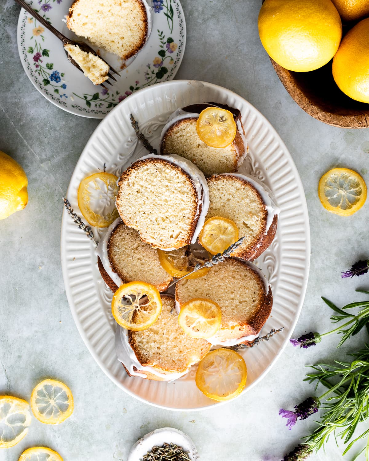 oval platter with glazed bundt cake slices topped with lavender and candied lemon slices