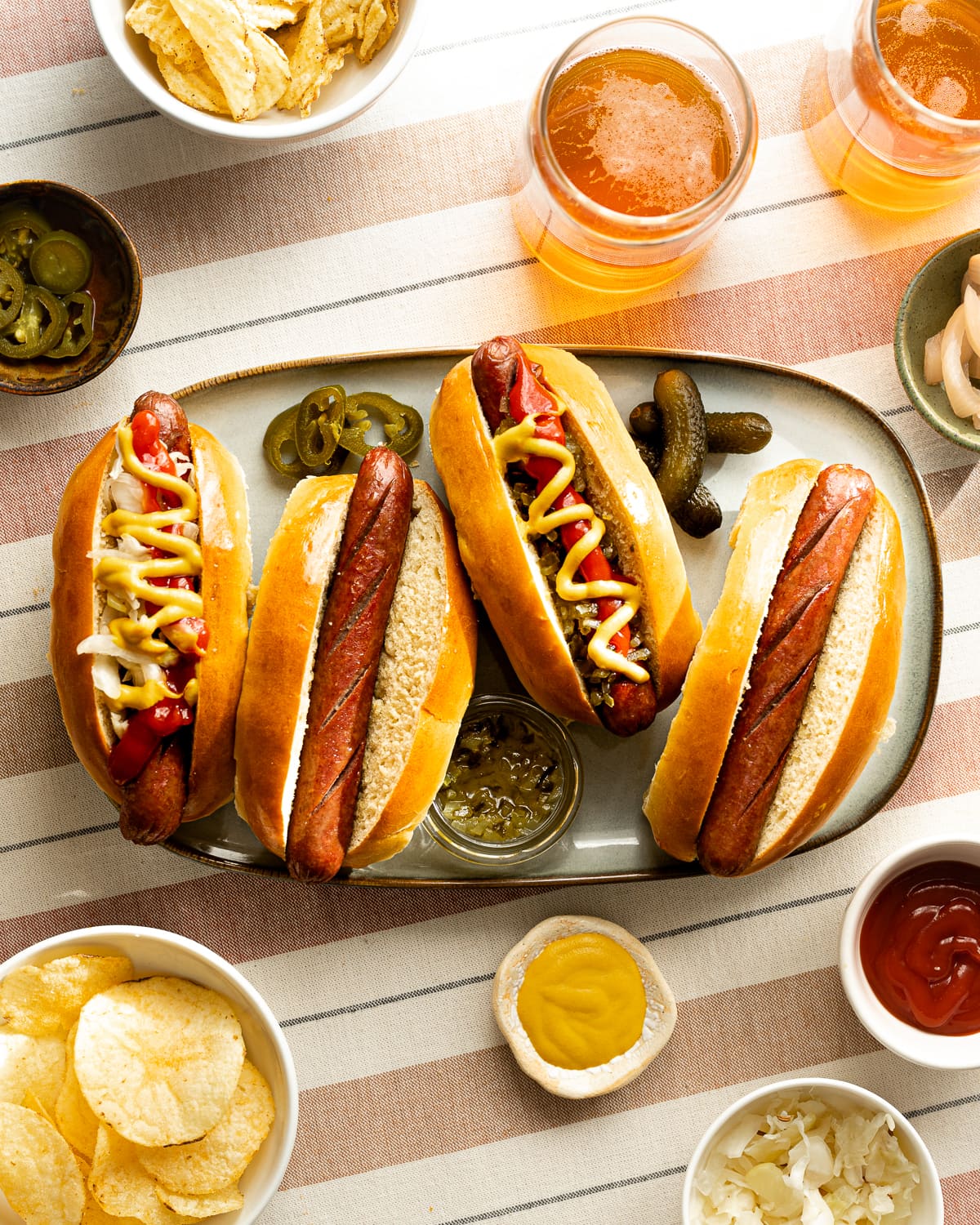 Hot dogs in hot dog buns topped with ketchup, mustard relish and sauerkraut on a platter. 