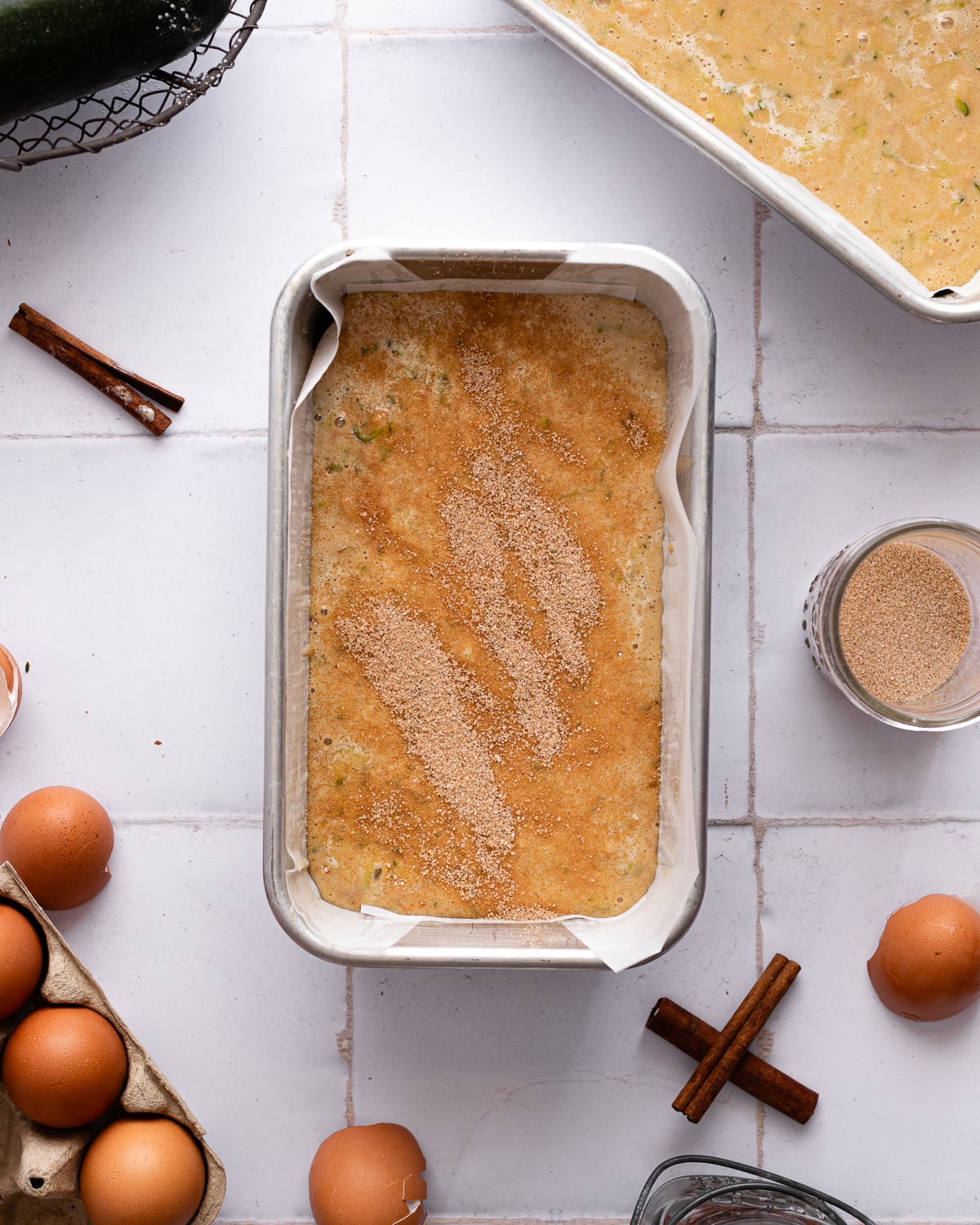 Zucchini bread batter in a loaf tin with cinnamon sugar on top. 