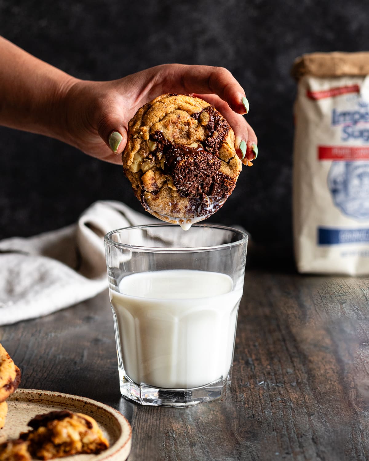 large chocolate chip cookie dipped in a glass of milk.