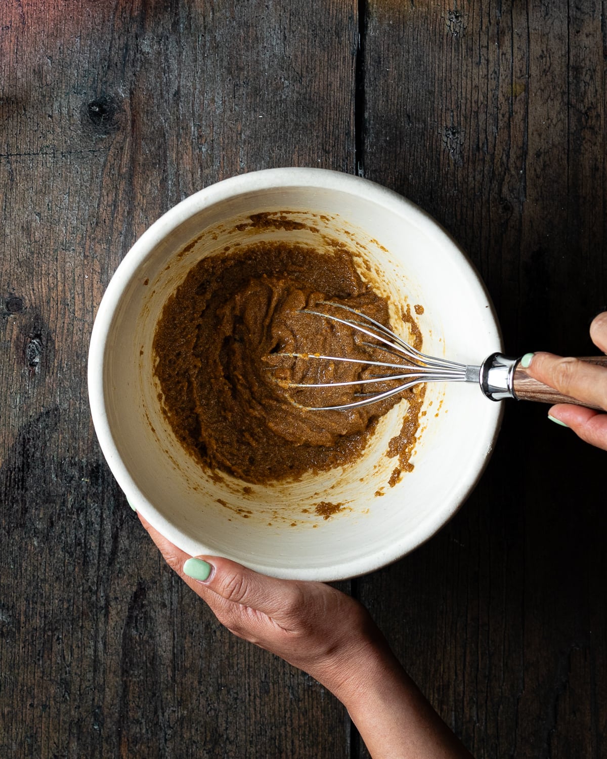 hand whisking sugar and butter together in a white bowl. 