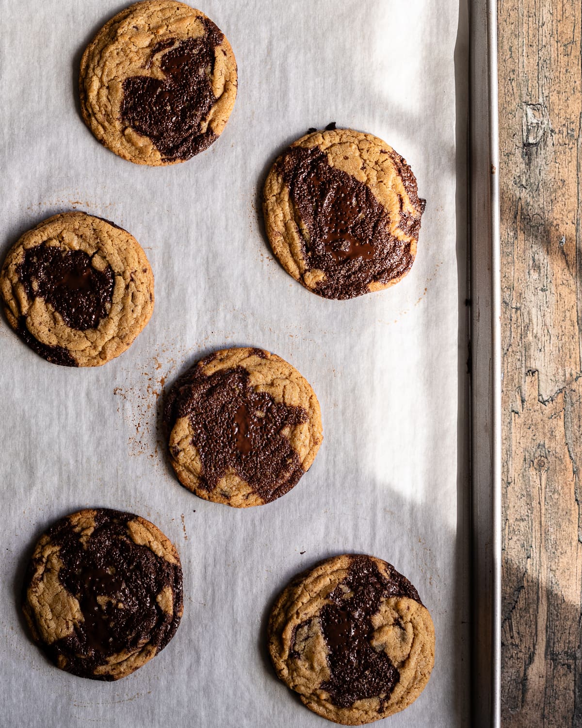 baked chocolate chip cookies on a parchment-lined baking sheet.