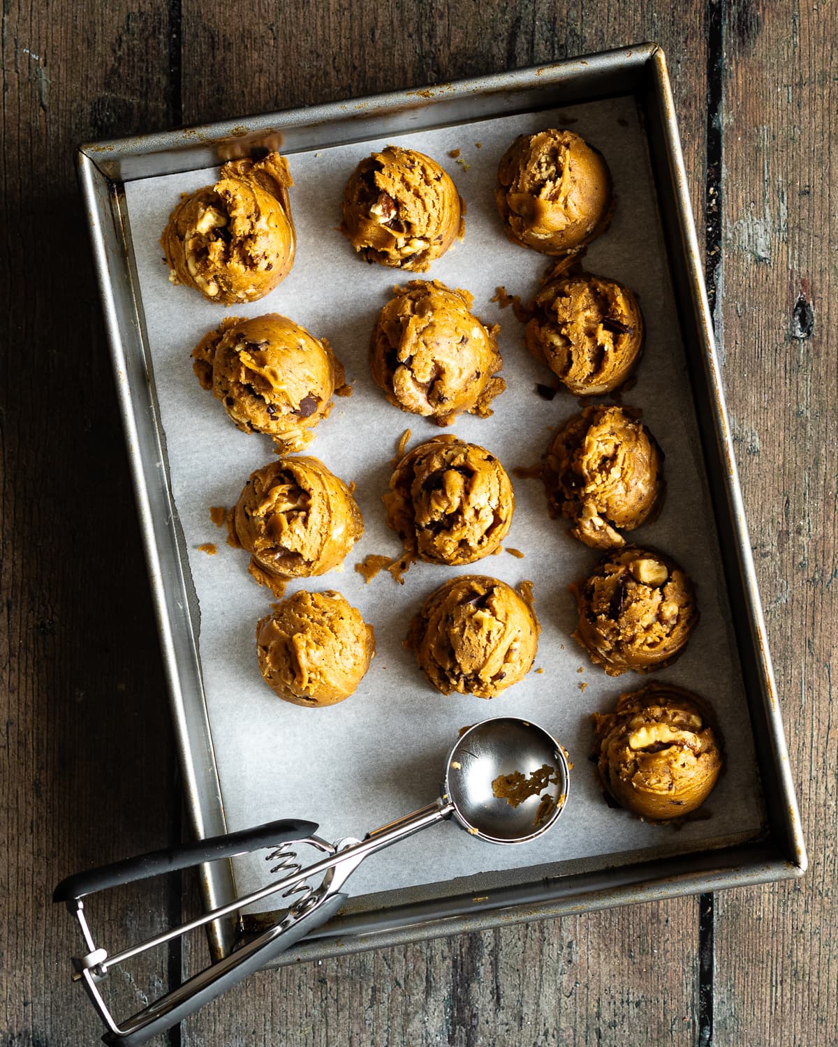 cookie dough balls in a baking pan lined with parchment paper.
