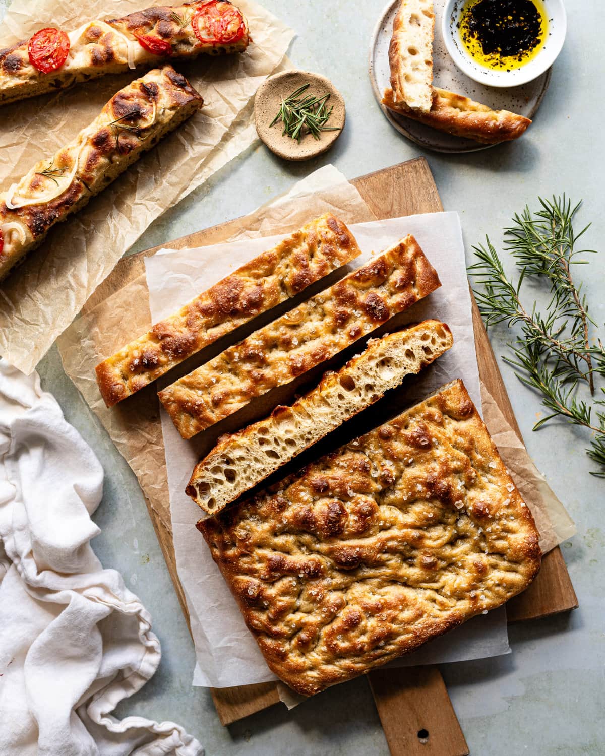 A whole focaccia sliced on a wood cutting board.