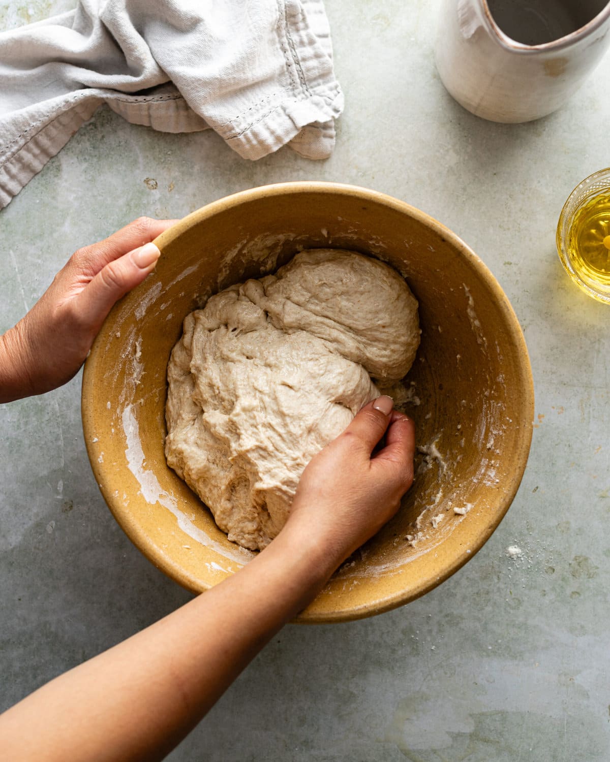 Hands kneading dough inside a bowl.