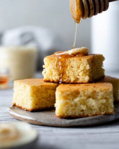 stack of cornbread with a pat of butter and honey drizzled on top