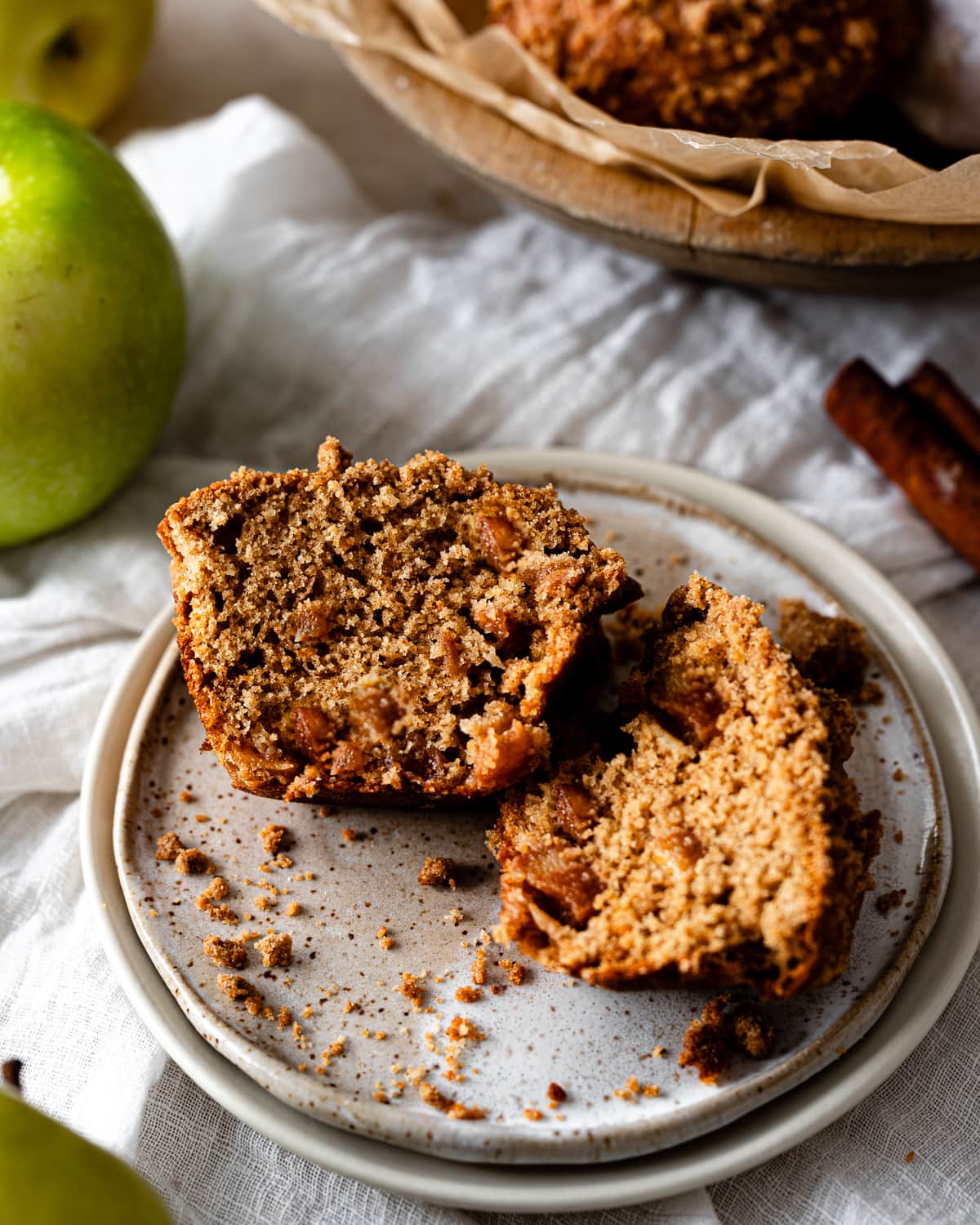 Muffin cut in half with pieces of apples on a saucer. 