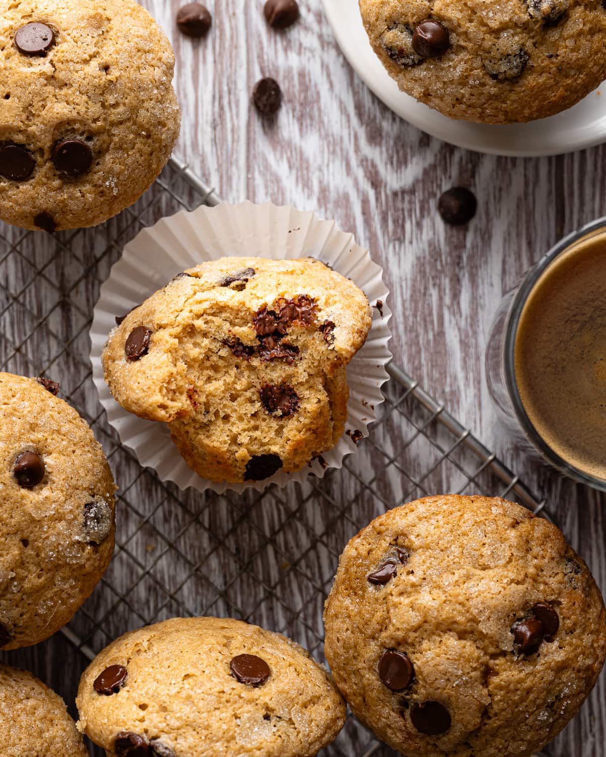 muffin with liner pulled back with a bite taken out on a wire rack. 