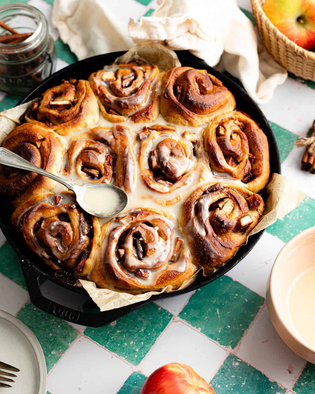 Baked cinnamon rolls topped with glaze in a cast-iron skillet. 