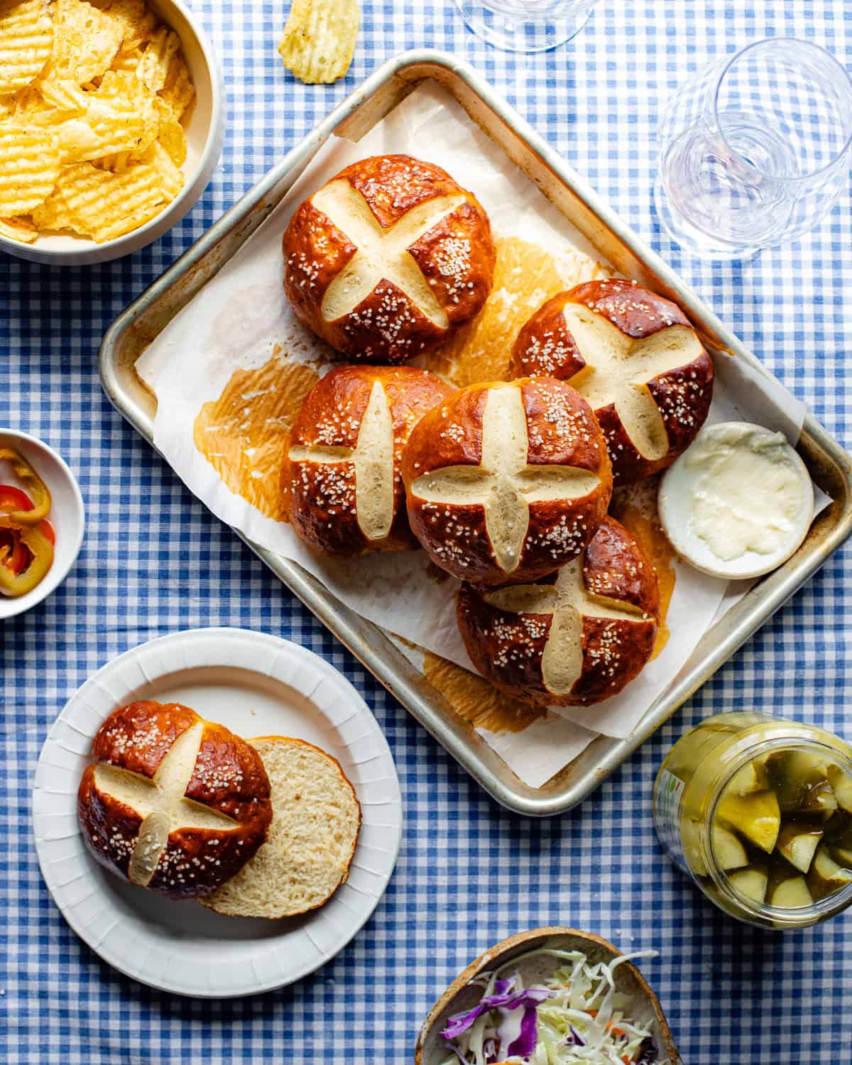 Sourdough discard pretzel buns stacked on a baking tray.