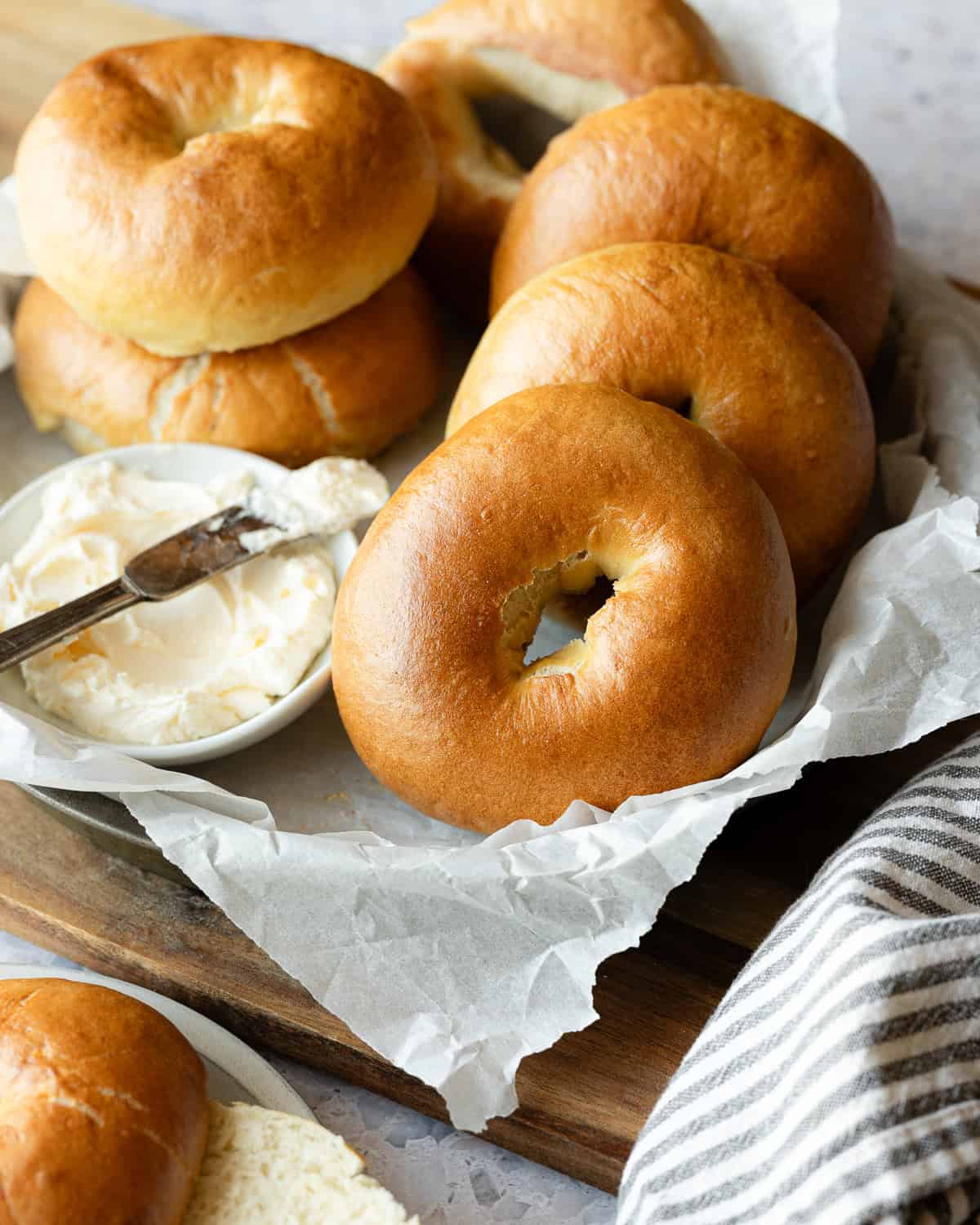 Bagels and cream cheese on a pan lined with parchment paper. 