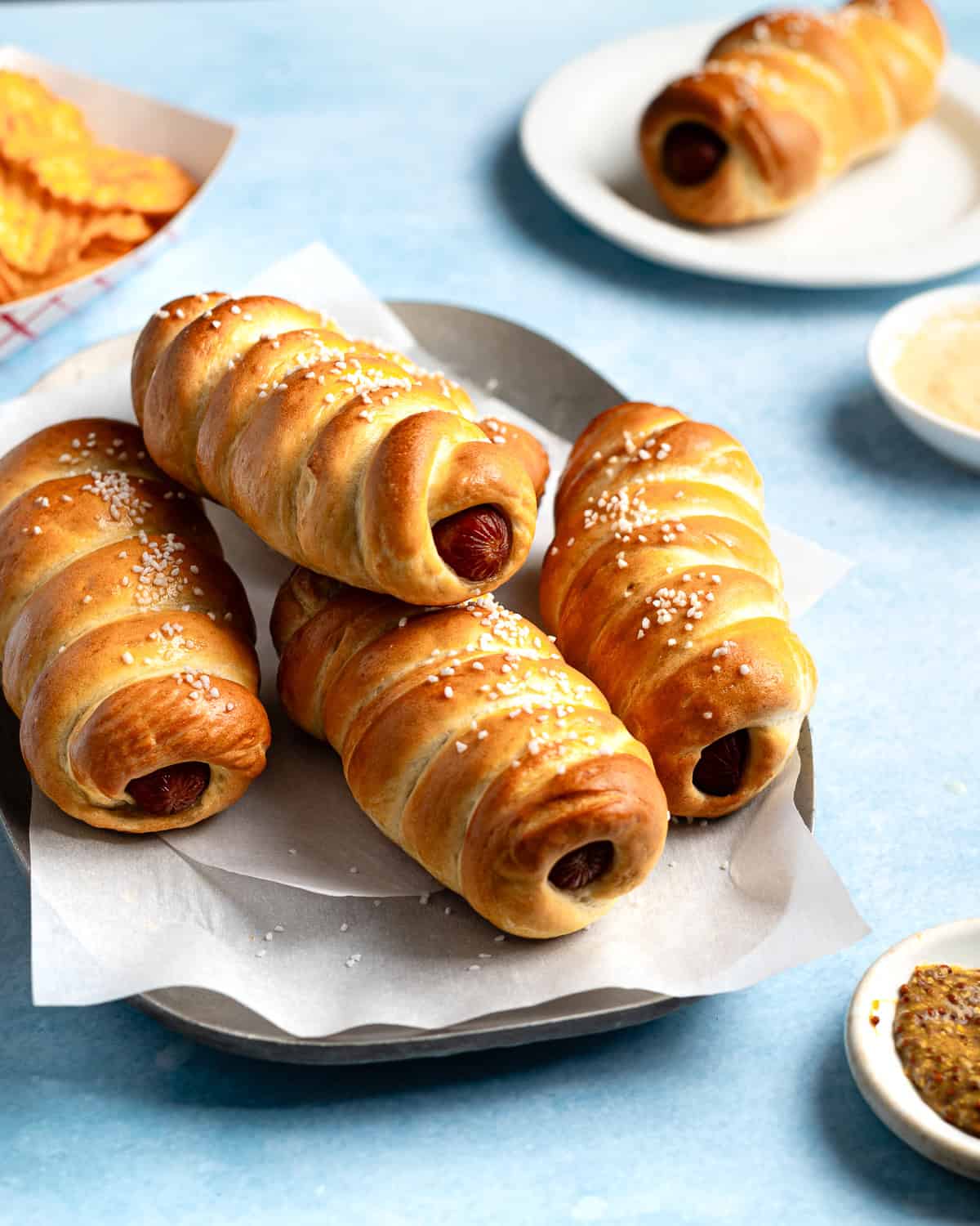 Pretzel Dogs stacked on a platter lined with parchment paper.