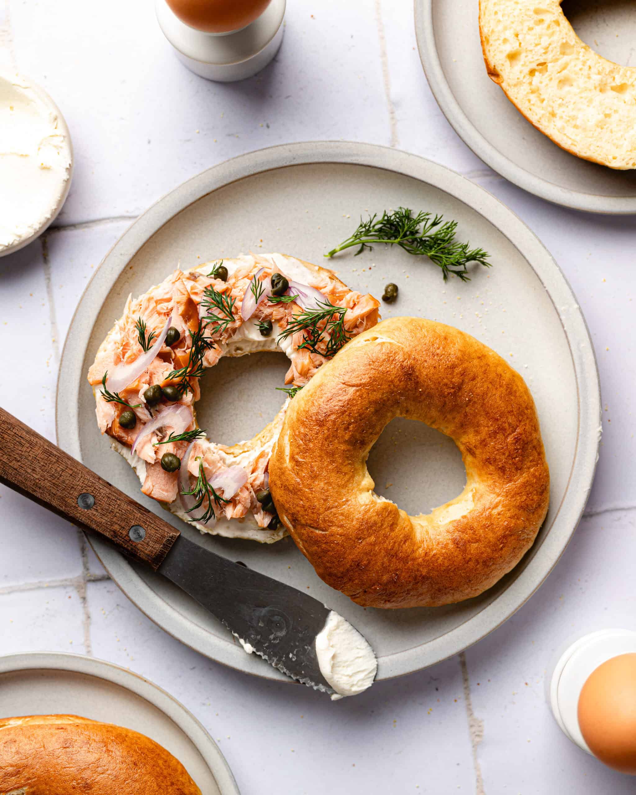 Split bagel with smoked salmon, cream cheese, capers, dill and shallots on a salad plate.