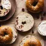 Sliced cranberry orange bagels on a piece of parchment paper.