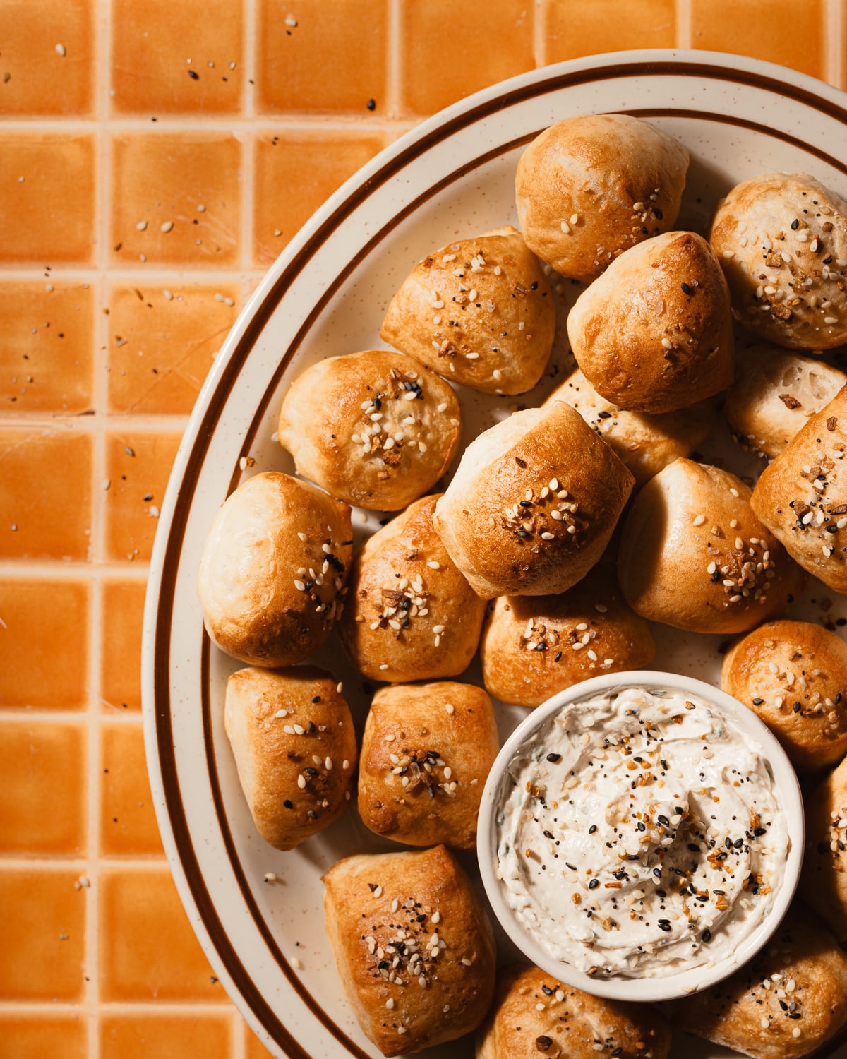 A platter with a bowl of everything bagel cream cheese dip and bagel bites.