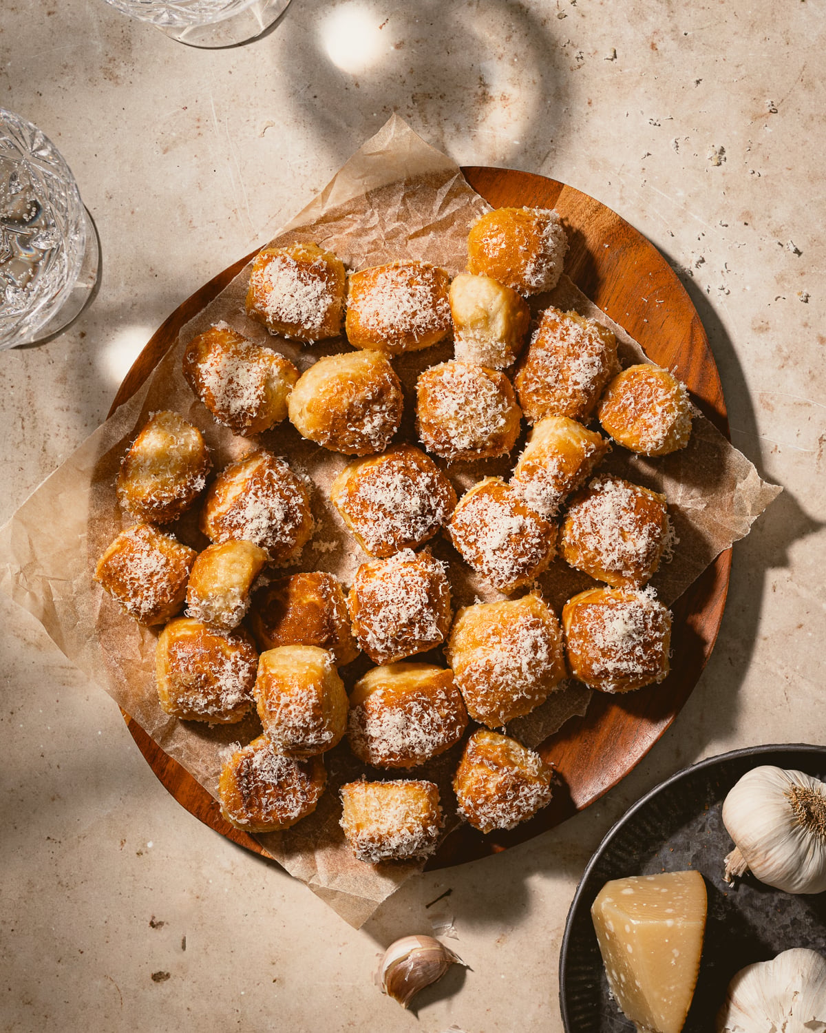 Garlic parmesan pretzel bites on a wooden platter lined with parchment paper. 