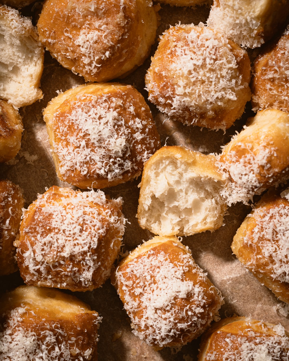 Pretzel bites on a piece of parchment paper with one torn in half. 