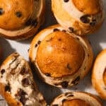 Chocolate chip brioche buns on a piece of parchment paper with one torn in half.