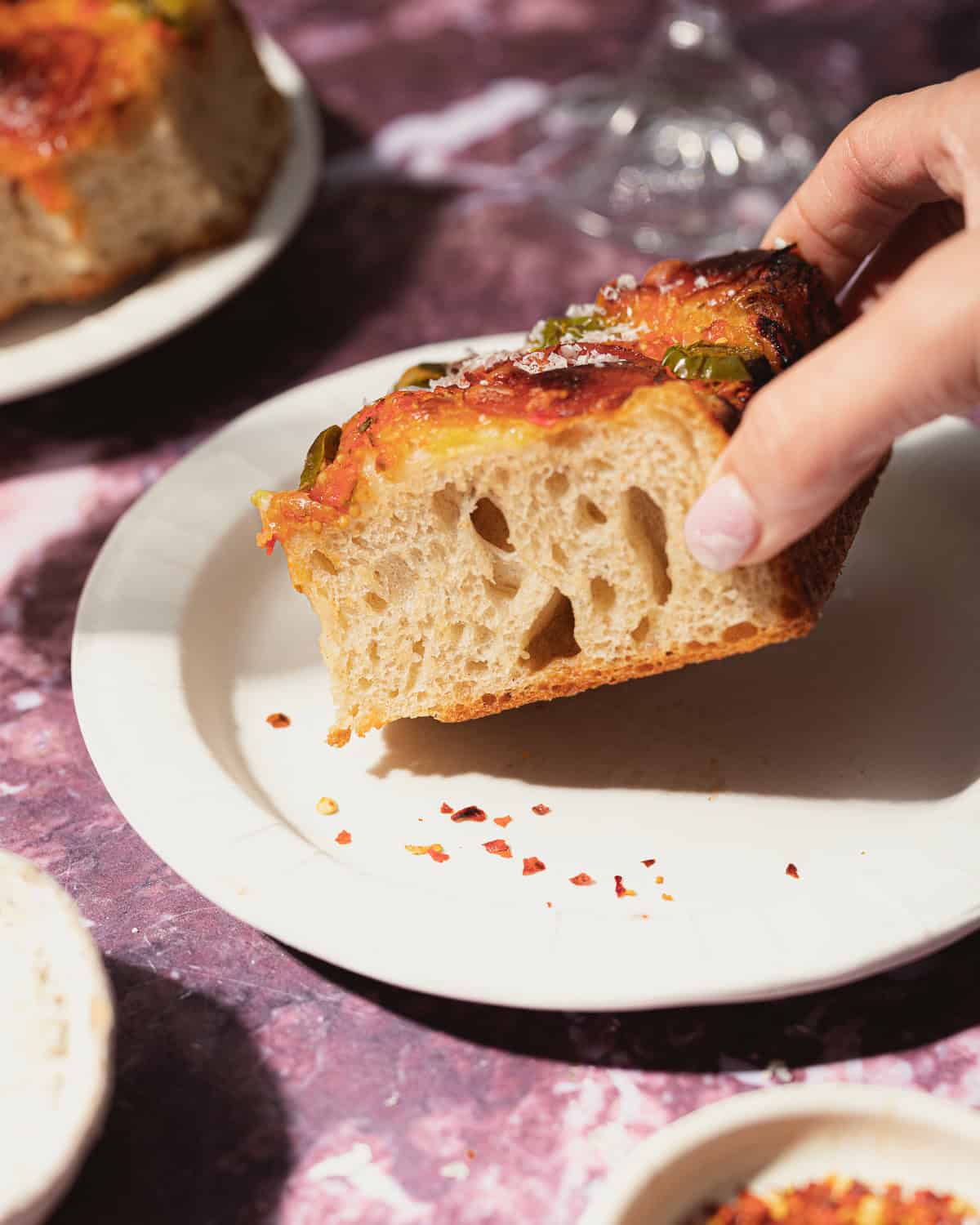 Hand picking up slice of focaccia pizza. 